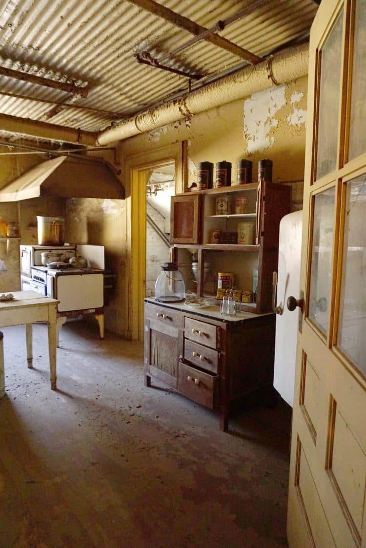 antique kitchen area with hutch, stove, and table in filthy abandoned space