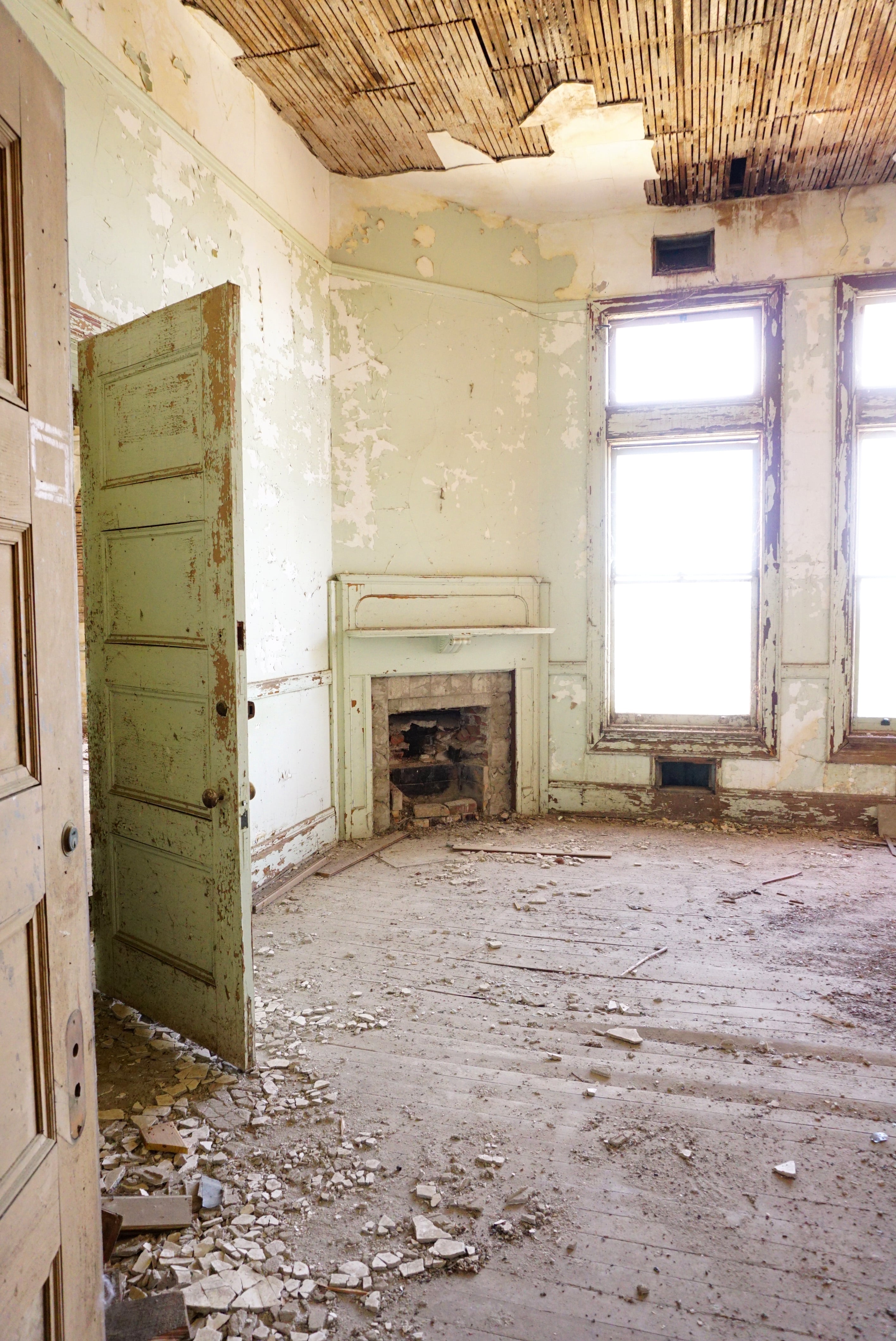 Room with mint green door and fireplace in ruins