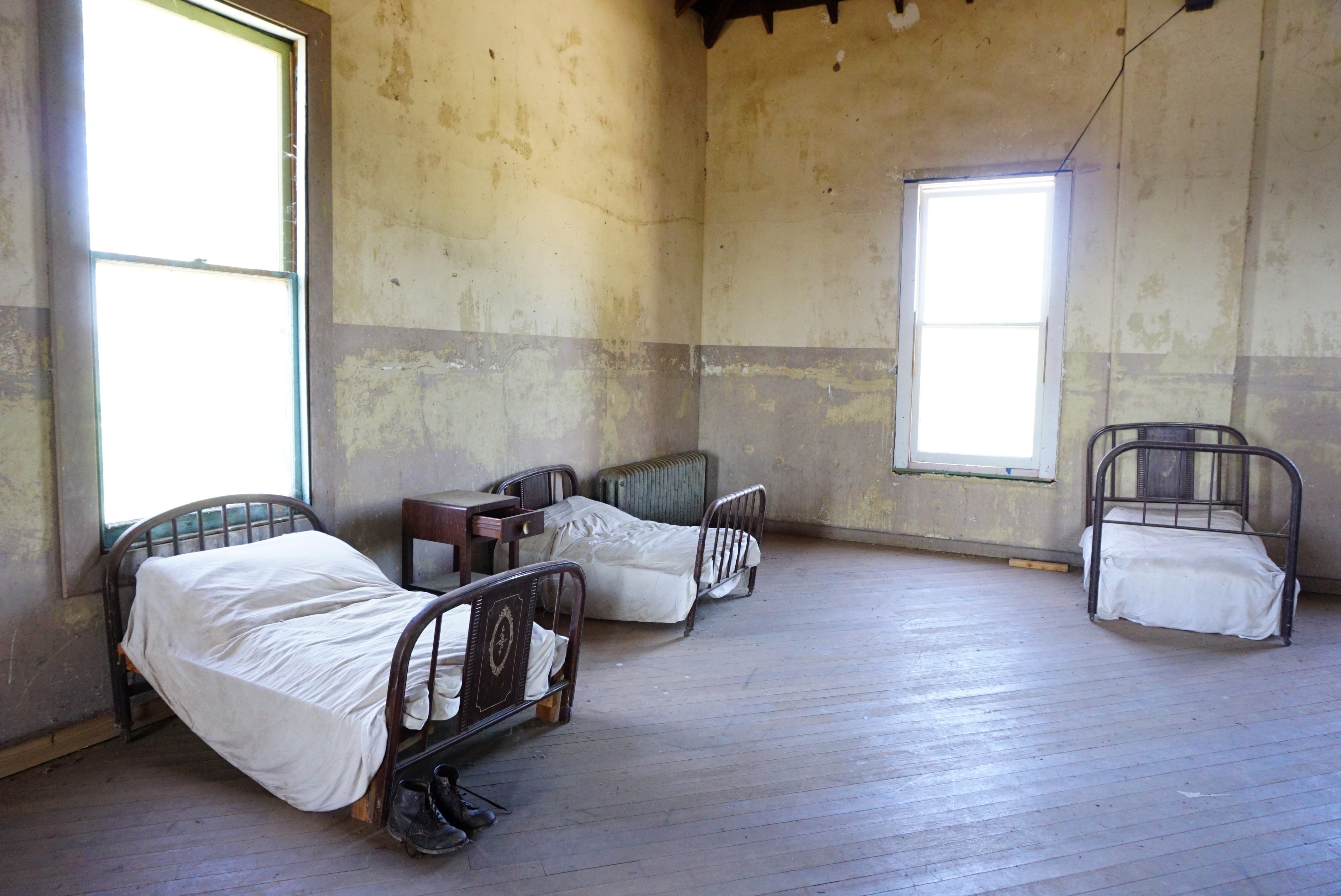 three metal single beds in a large room that is otherwise empty