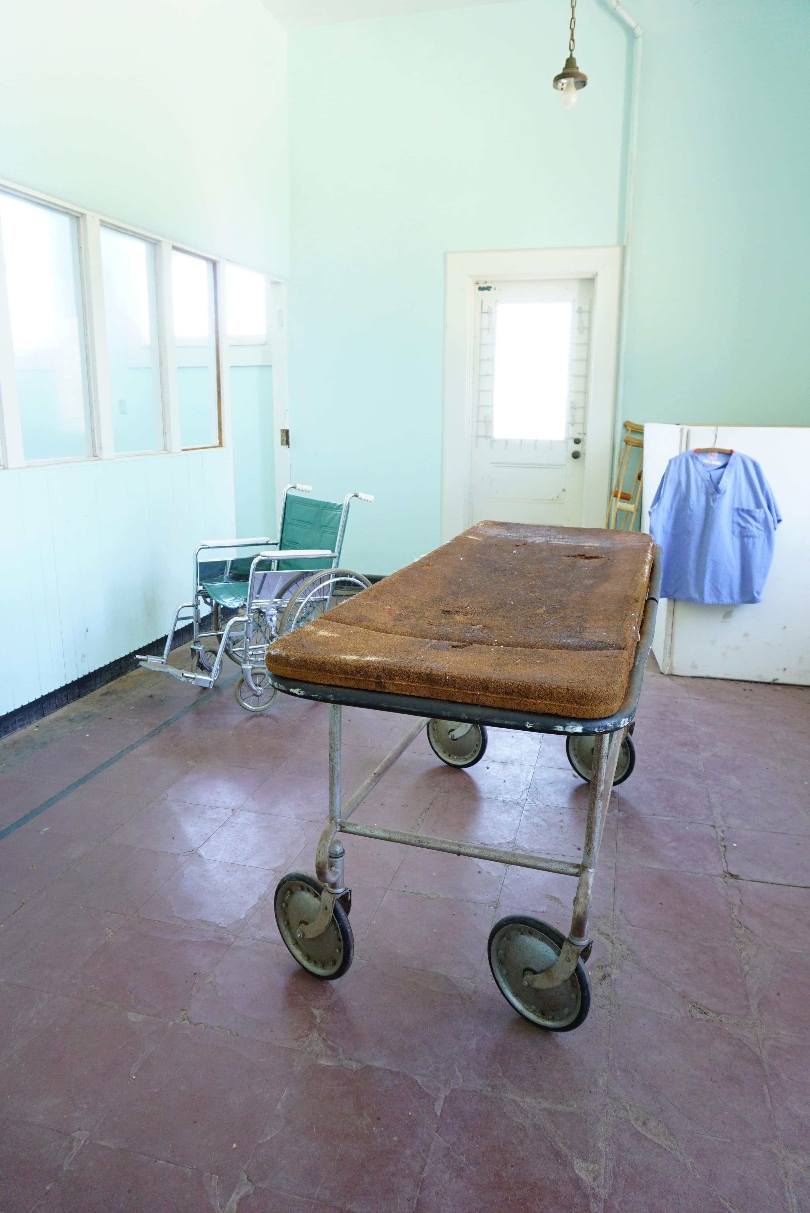 bright room with mint green walls and antique gurney, wheelchair, and crutches