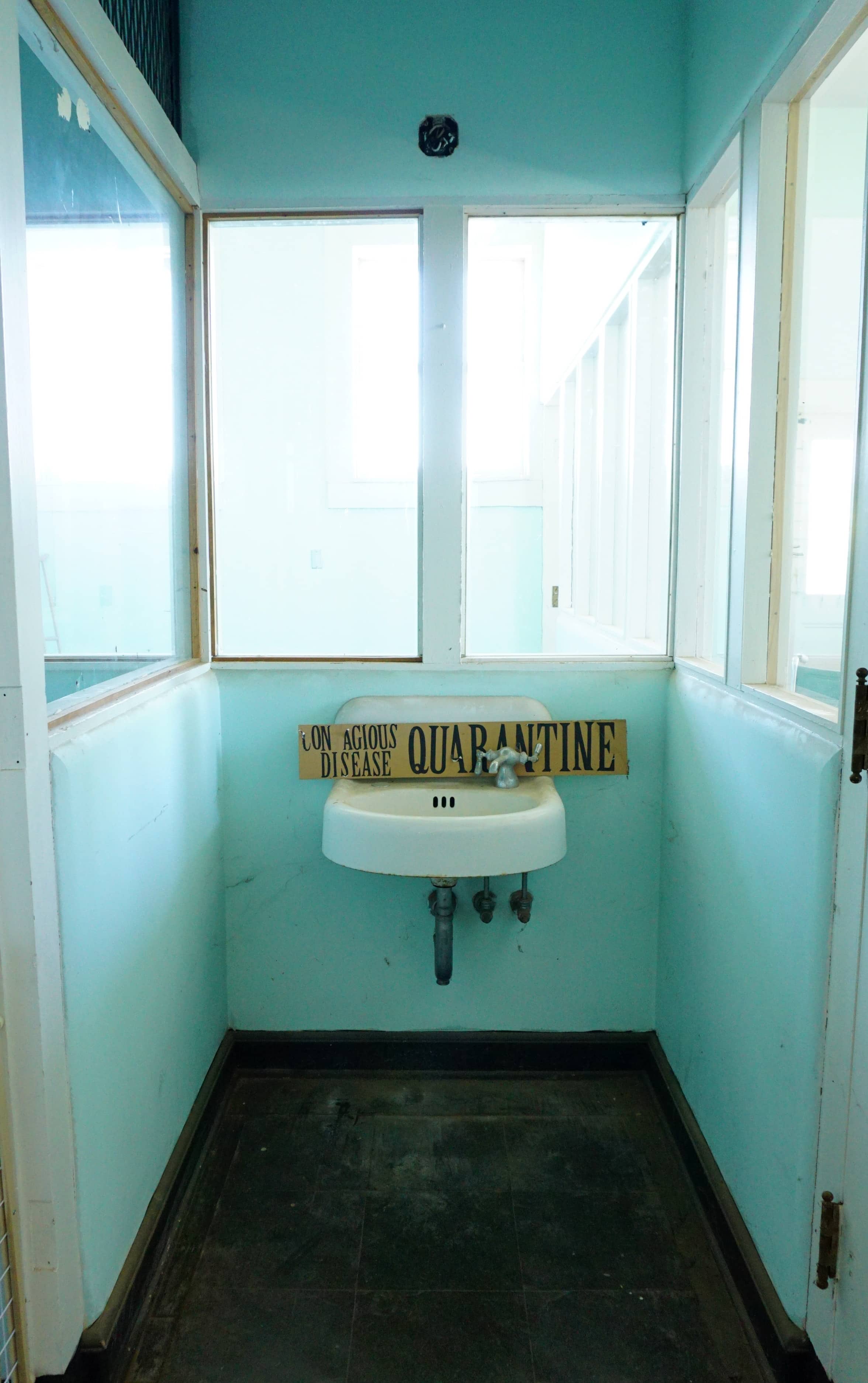 Yellow "contagious disease quarantine" sign on top of a broken white sink 