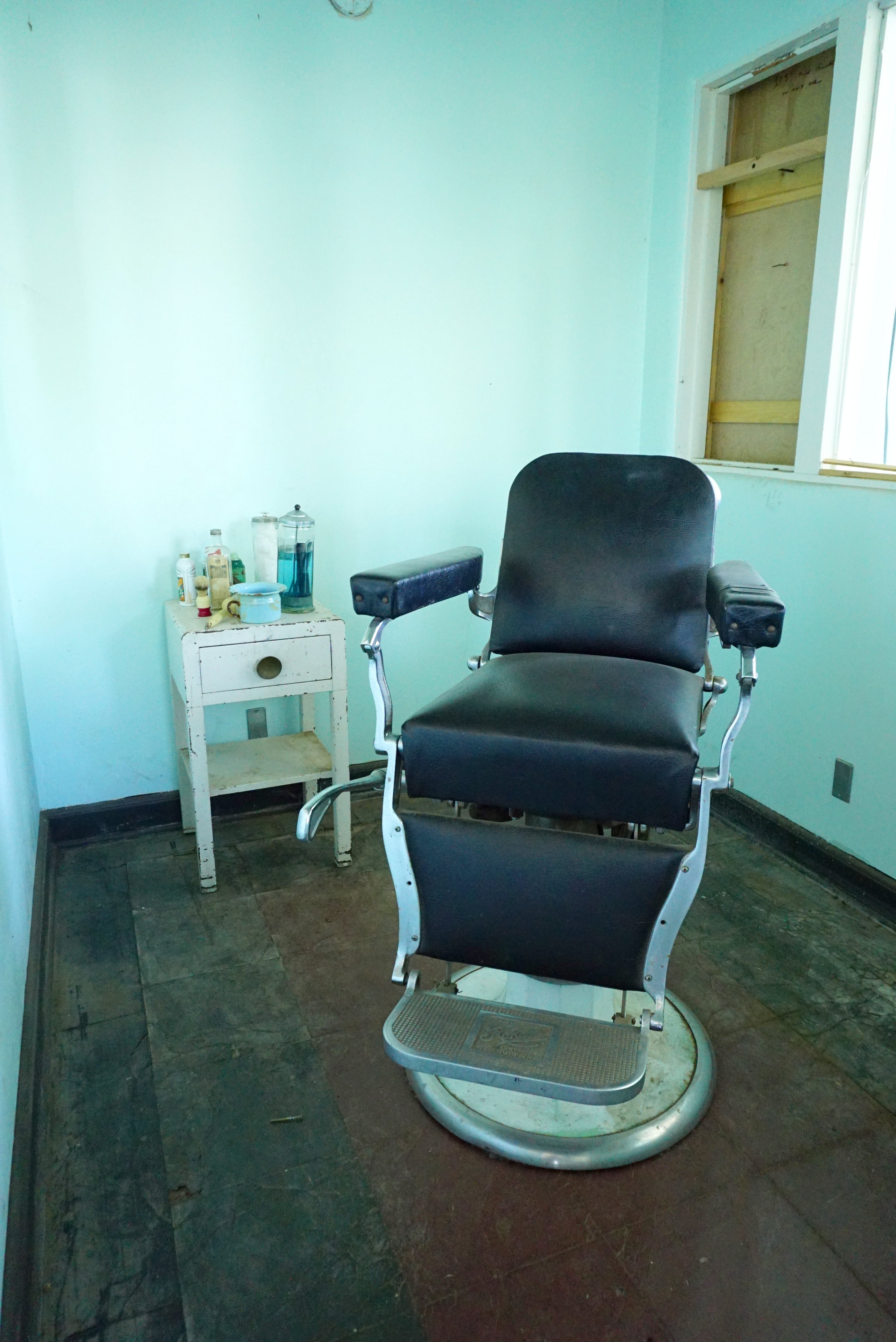 Antique barber chair and shaving supplies in a mint green room