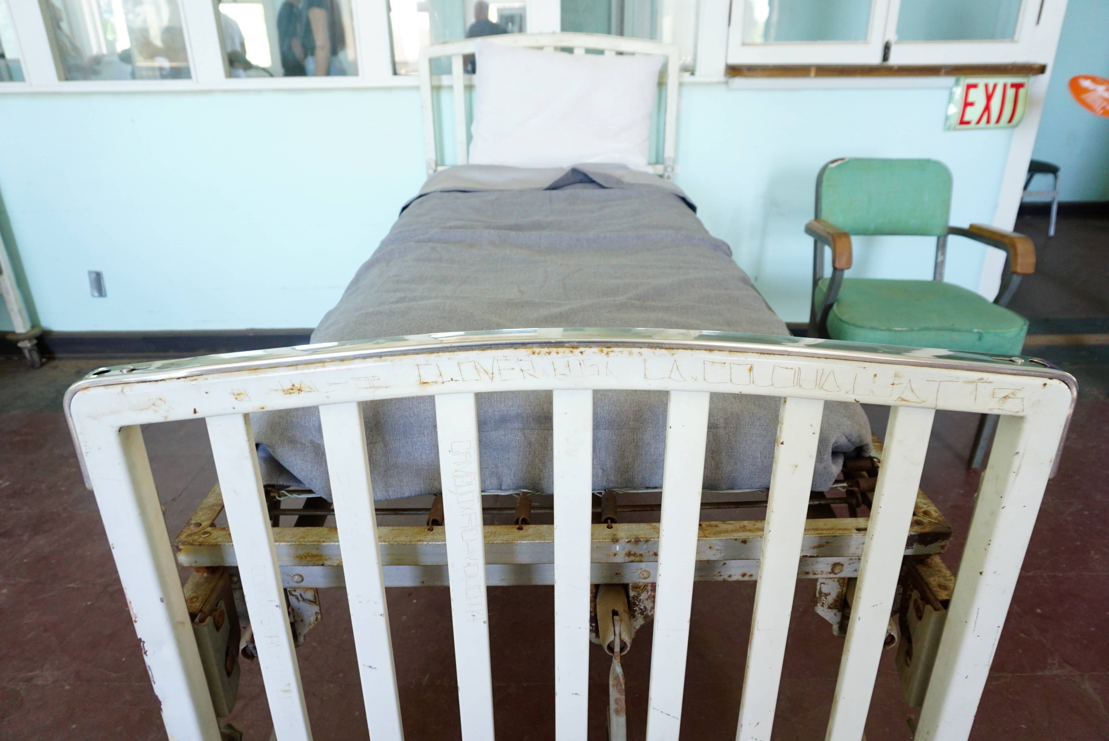 close up of names scratched into a rusty white hospital bedframe