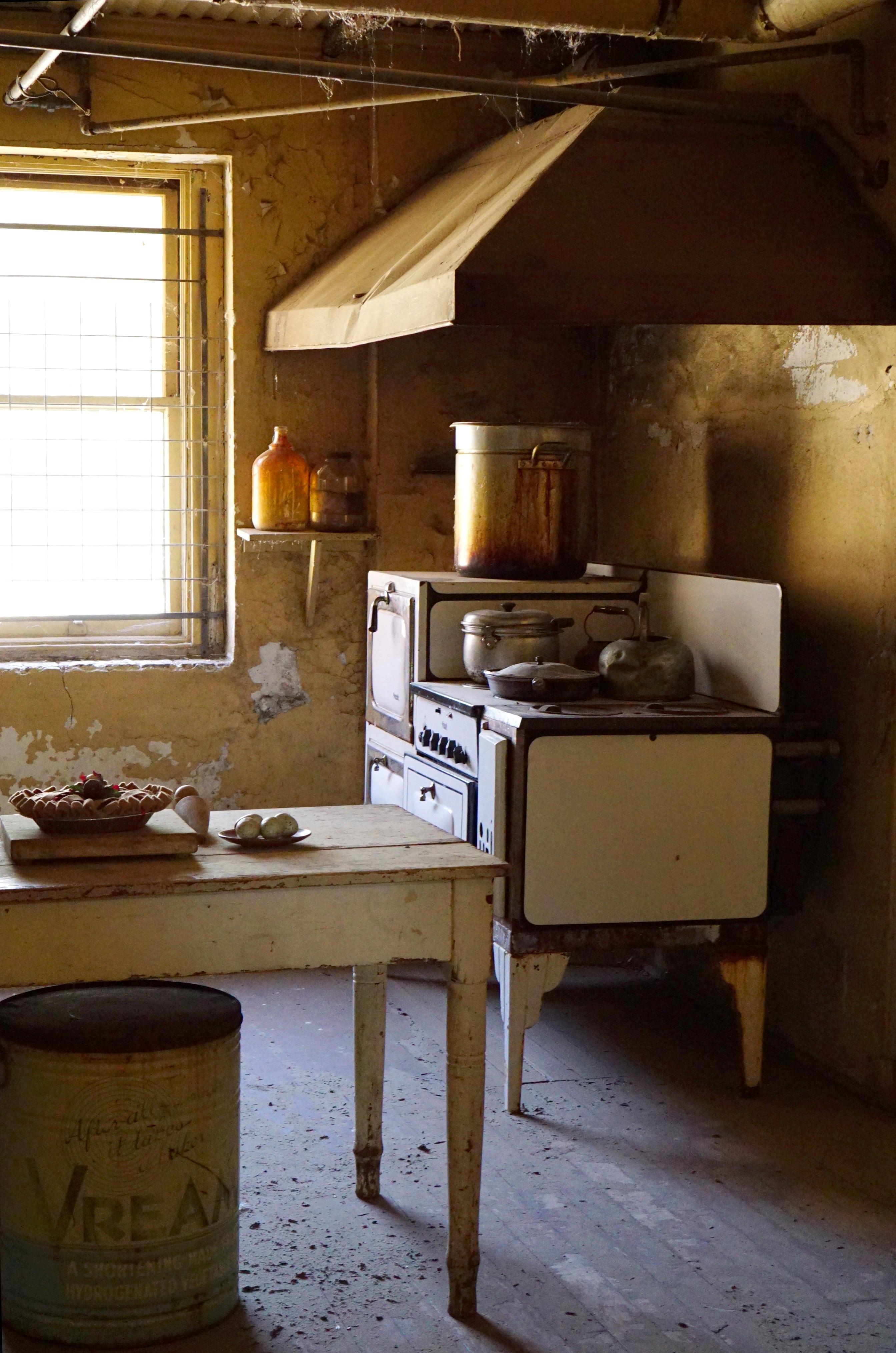 Kitchen with antique stove, room is filled with both sunbeams and spiderwebs