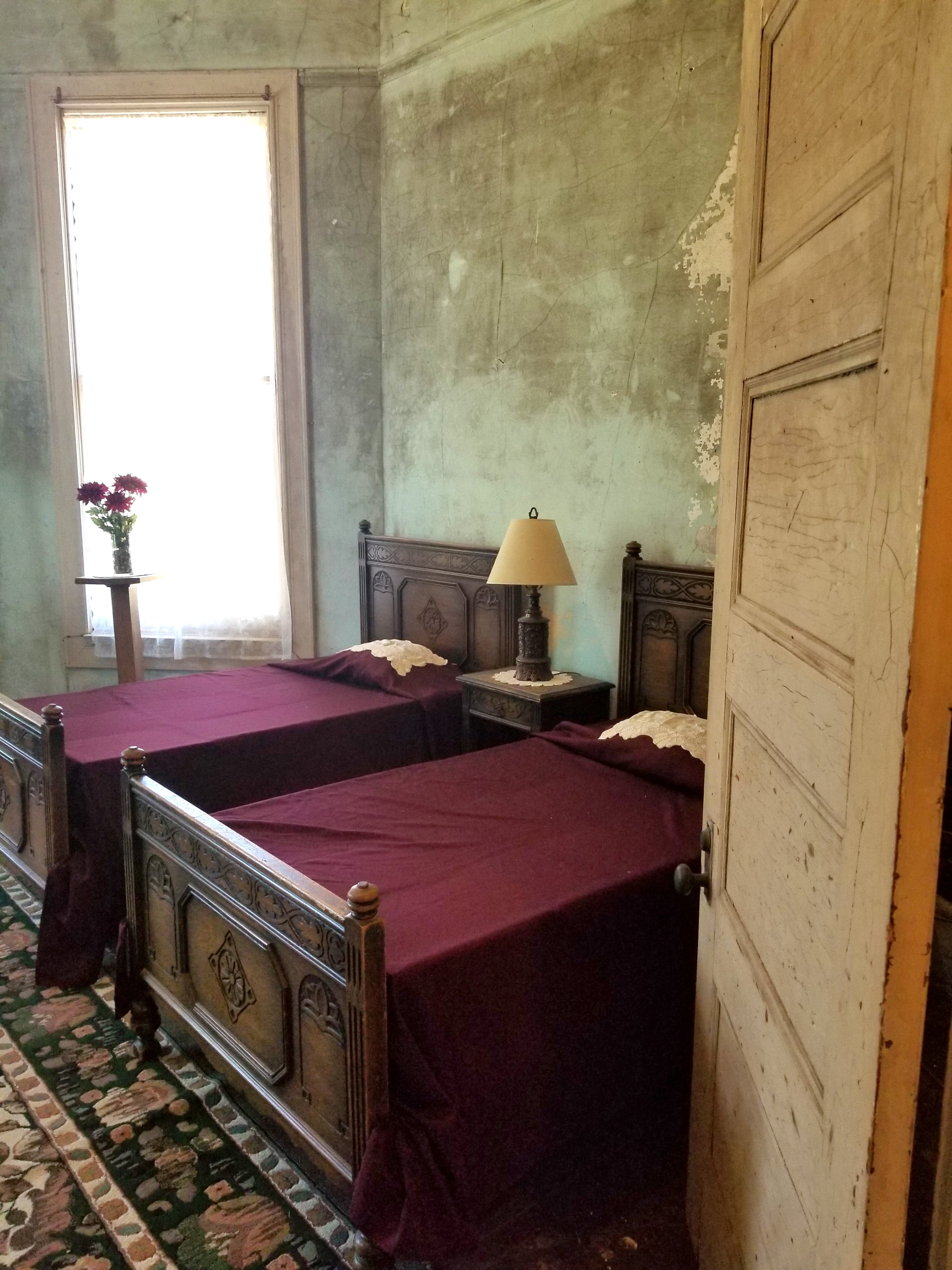 Two ornate wooden beds with burgundy bed cloths and doily pillows in bedroom