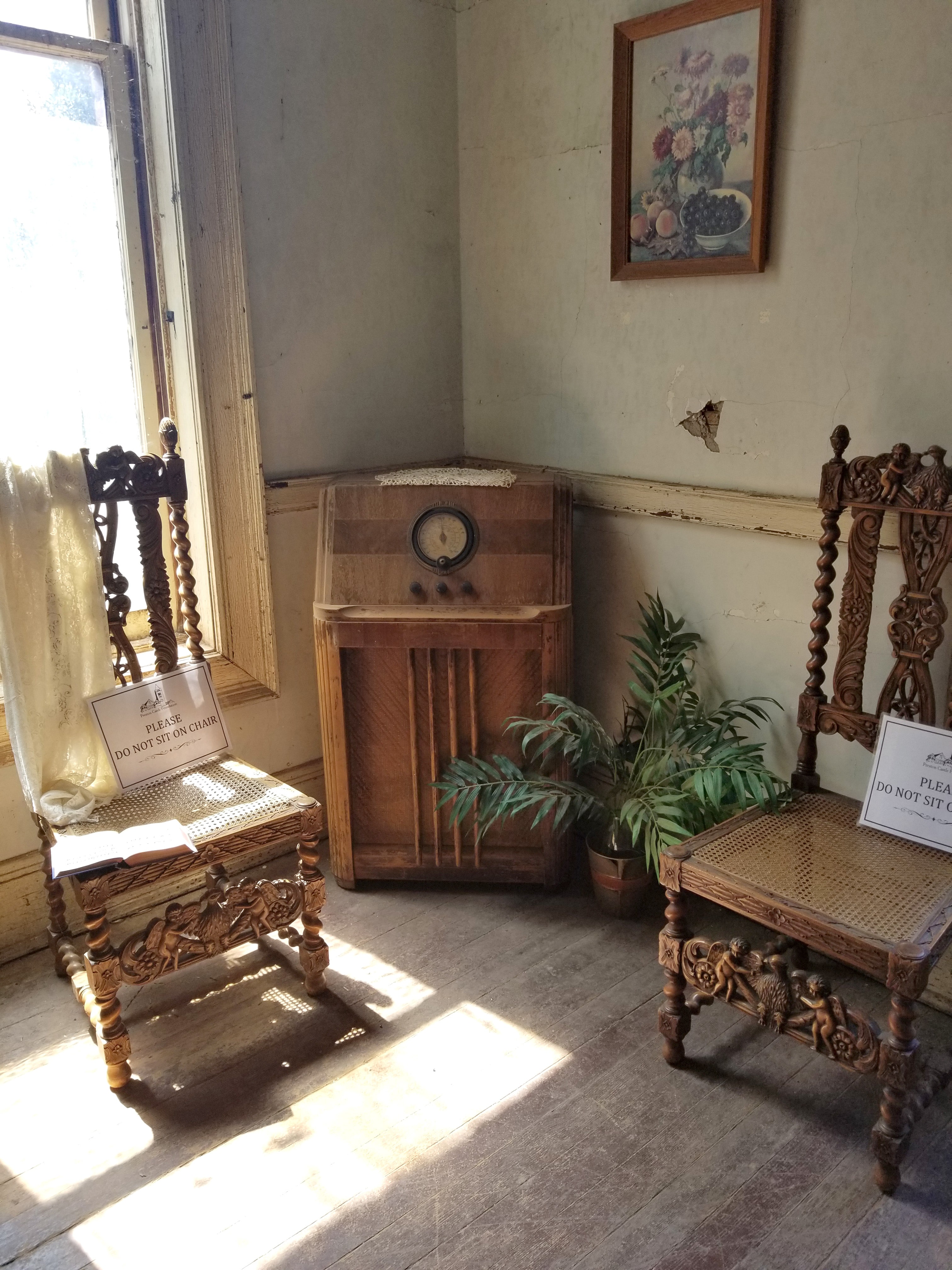 Two ornately carved chairs with angels and an antique console radio in apartment