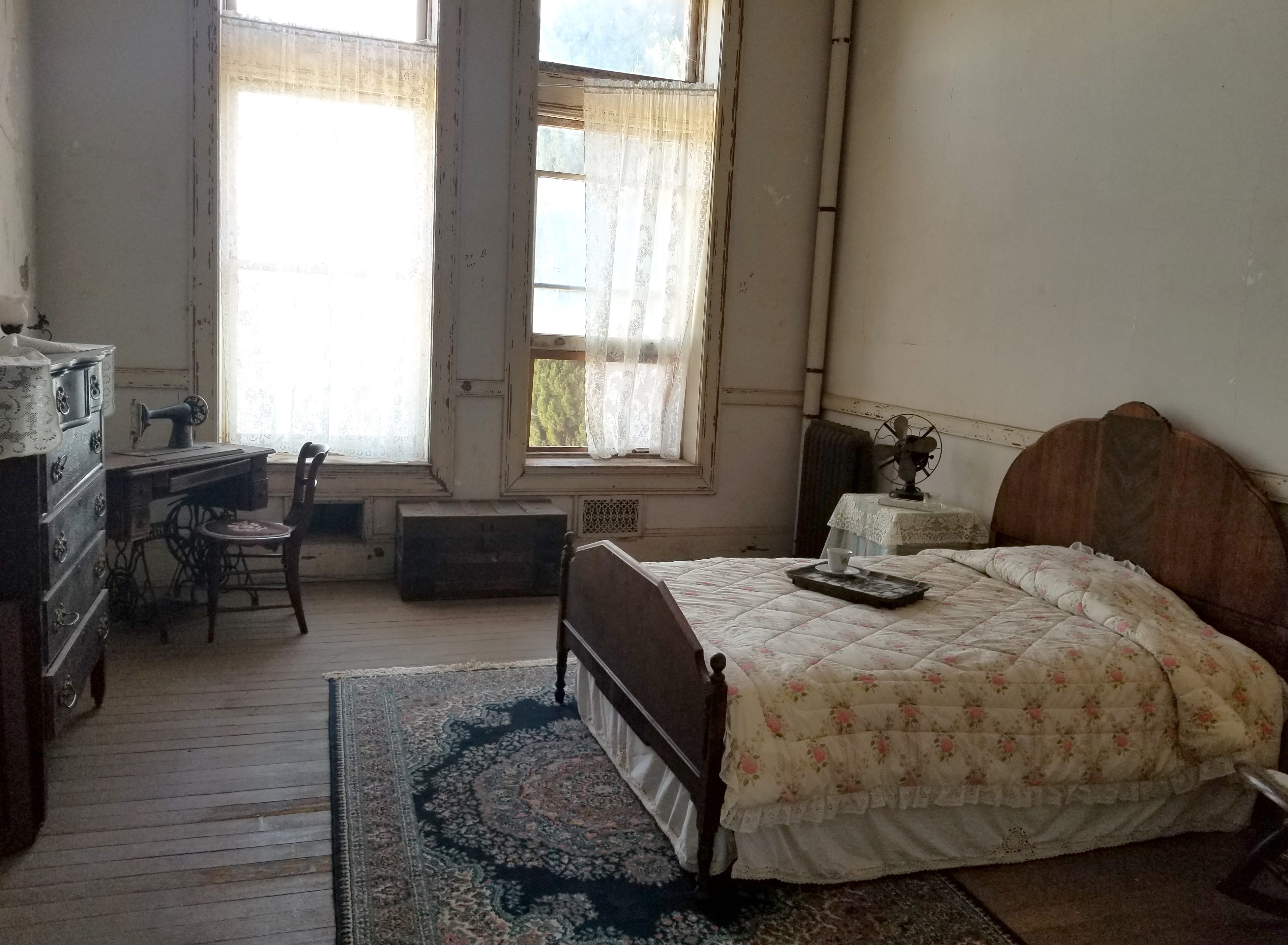 apartment with antique bed, sewing desk, dresser, chest, and rug