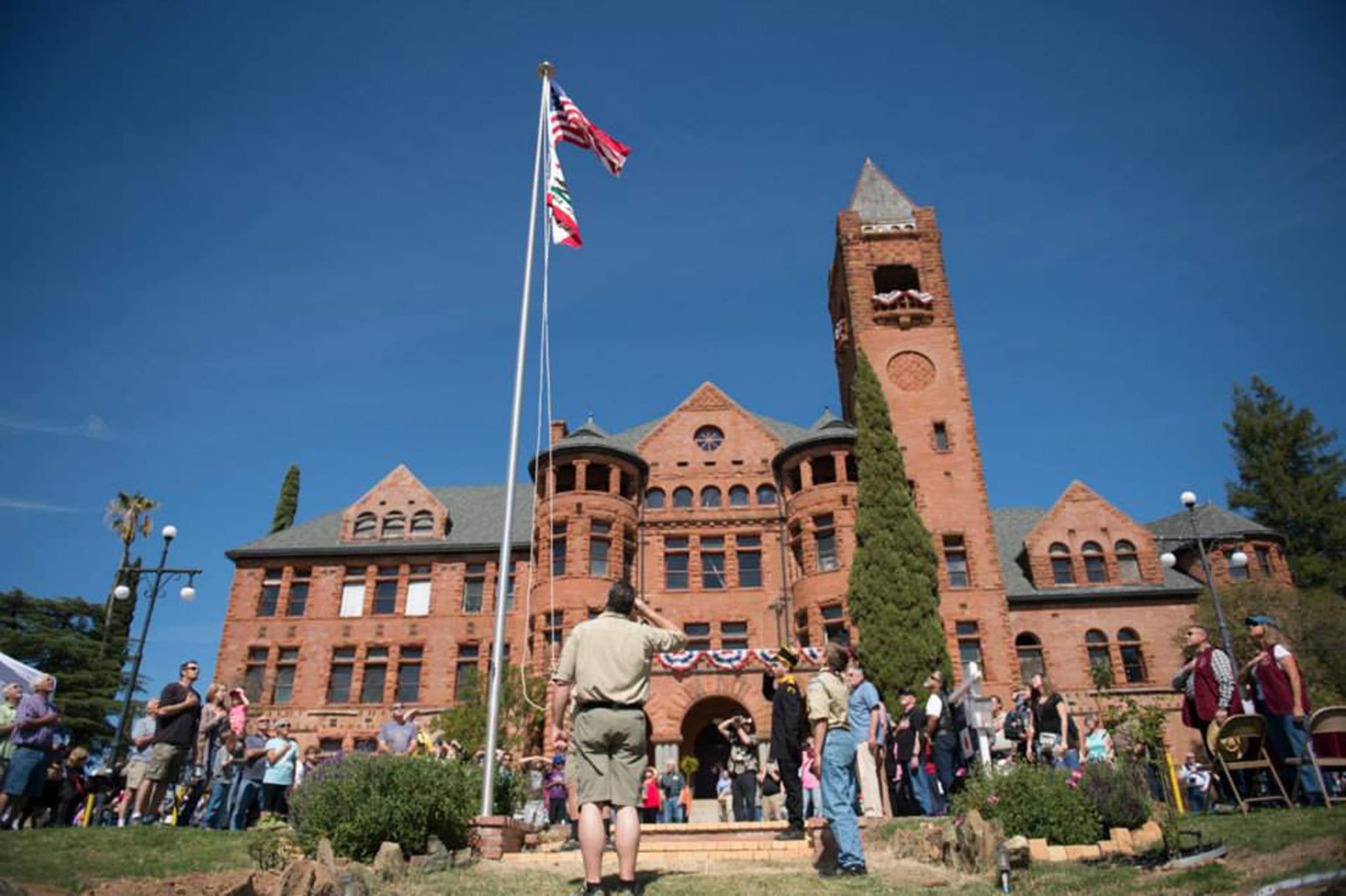 Crowd of people in front of Preston Castle at an event where they are all saluting the American flag 