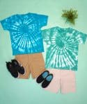 Two blue and green spiral tie-dye shirts on a mint green background with shorts and shoes