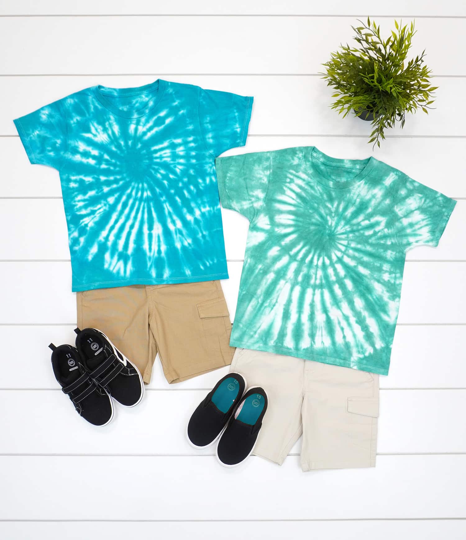 Two blue and green spiral tie-dye shirt on a white wood background with shorts and shoes