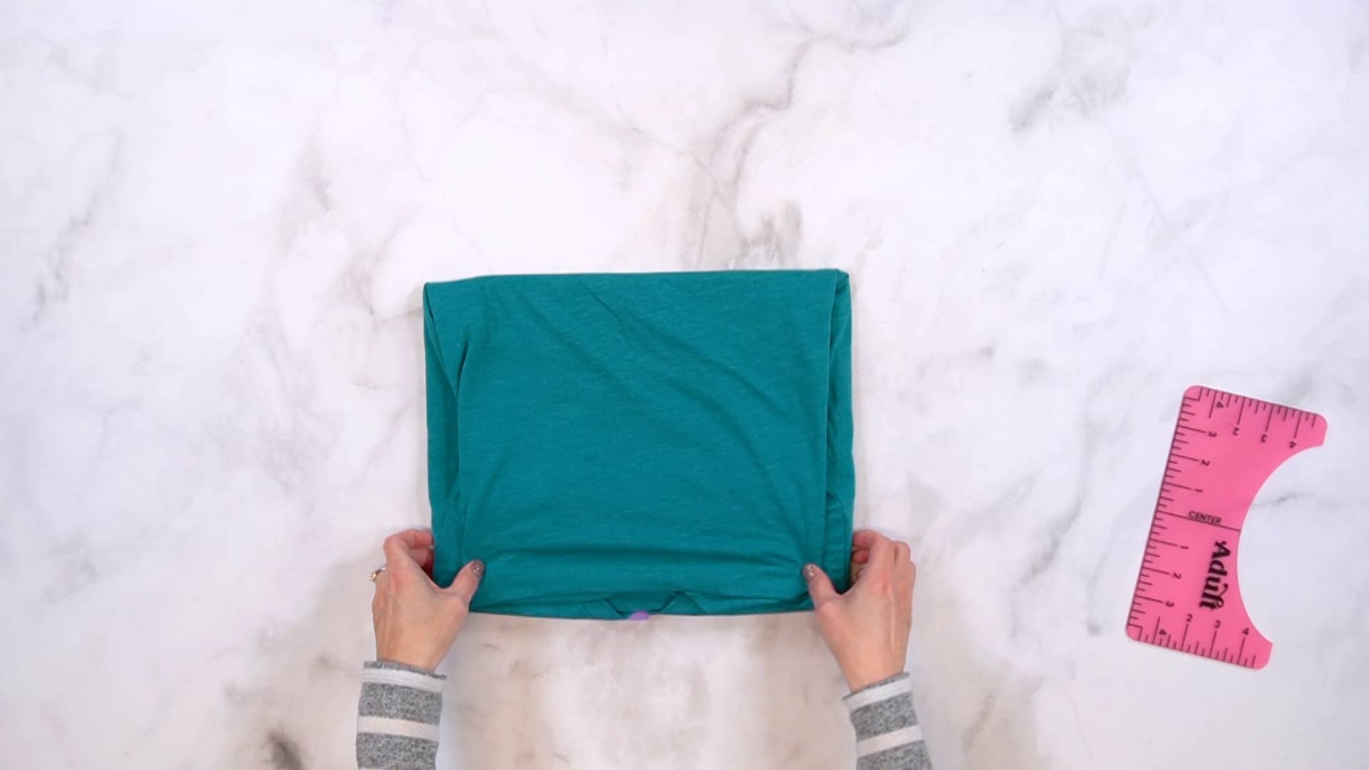 Hands folding a shirt into a rectangle shape