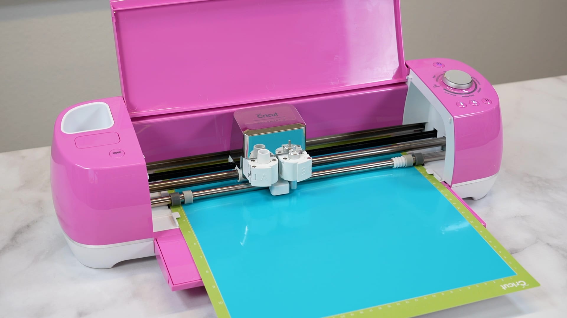 pink Cricut Explore Air 2 cutting bright blue vinyl on green Cricut mat