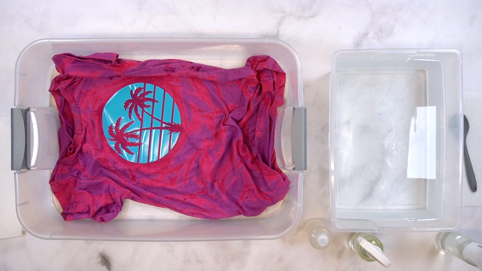 Partially bleached pink and purple shirt with blue vinyl design in a plastic tub