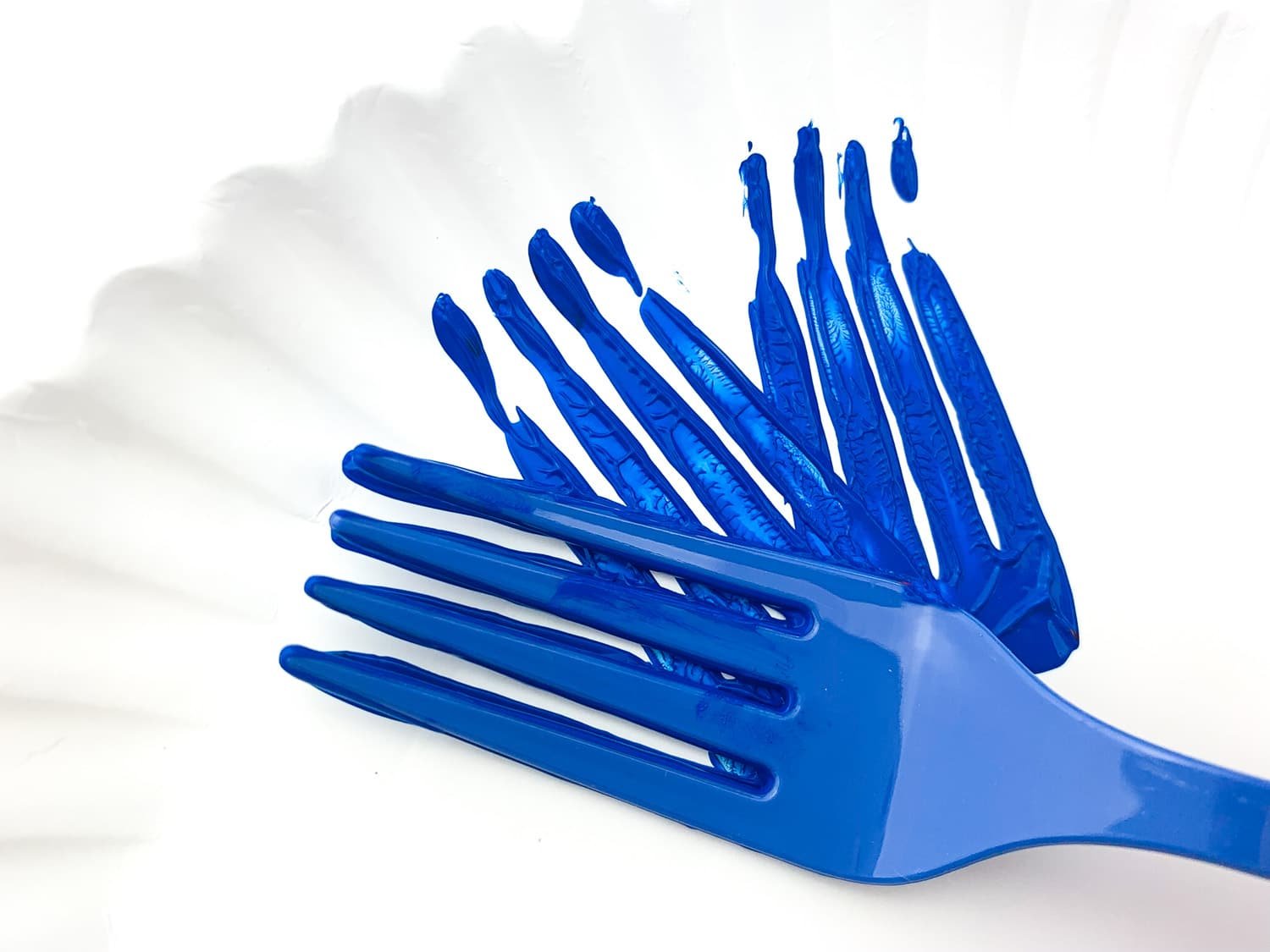 blue painted fork pressing firework pattern onto plate