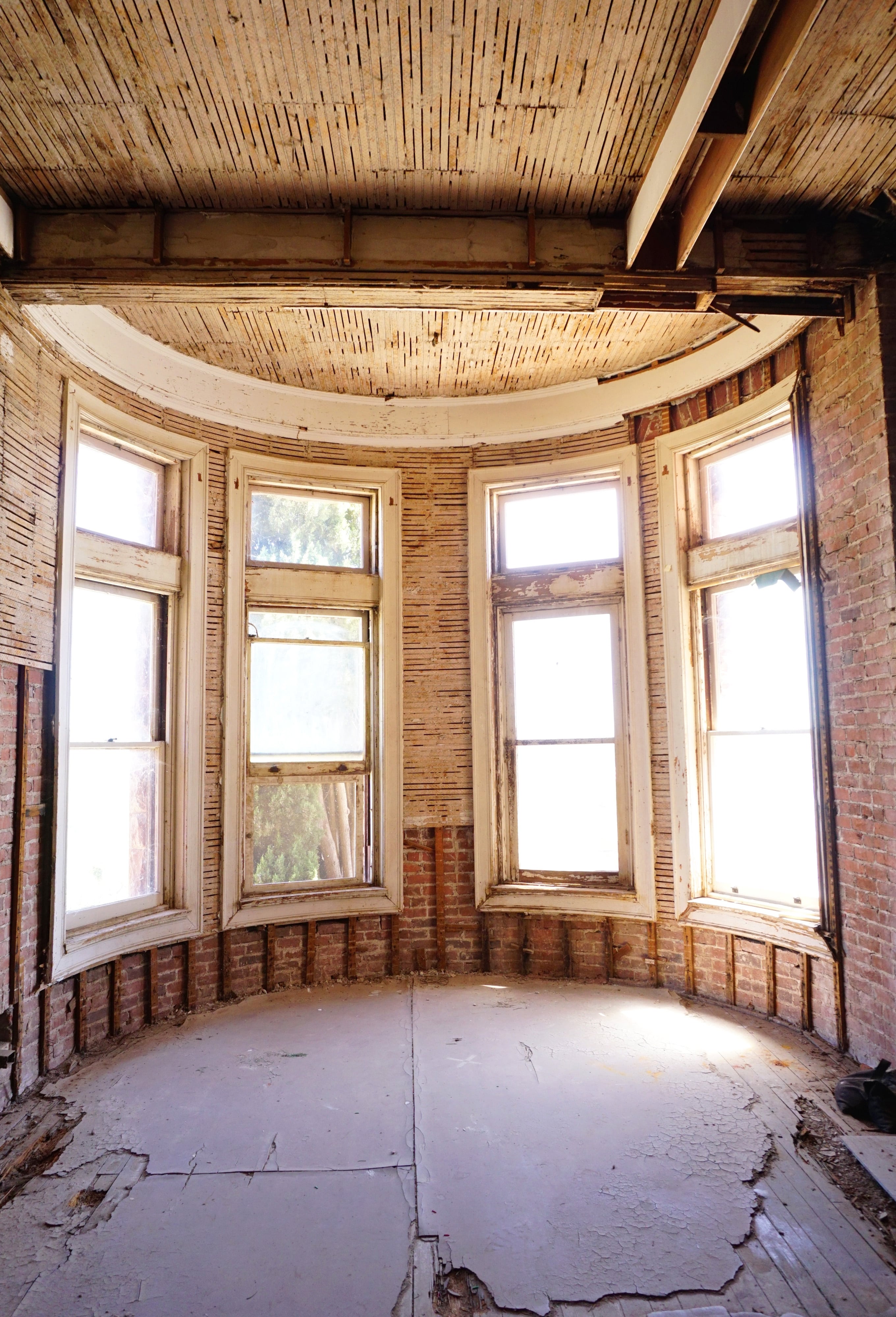 interior of curved portico in state of disrepair with exposed brick and lath