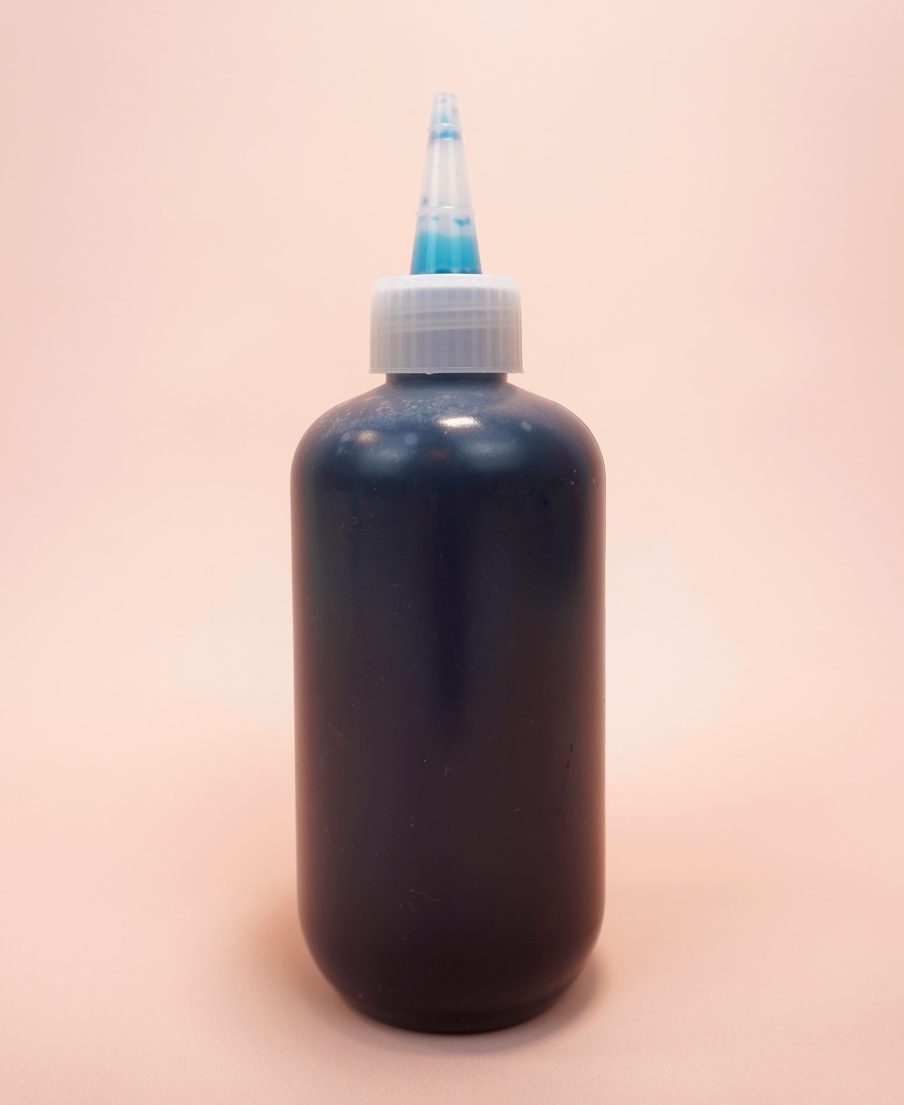 Dark teal blue fiber reactive dye in a squirt bottle on pink background