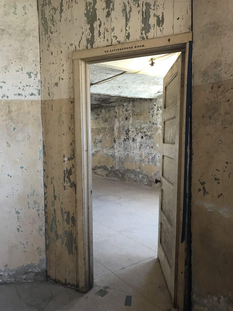 door in wall with peeling paint and mold and sign "to livingstone room"