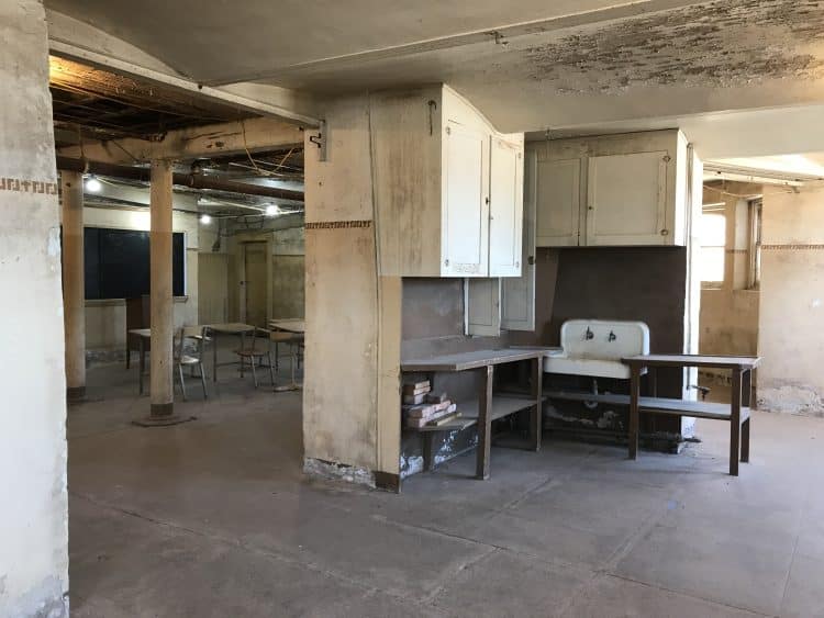 desks and tables in dirty and dingy basement room with peeling paint