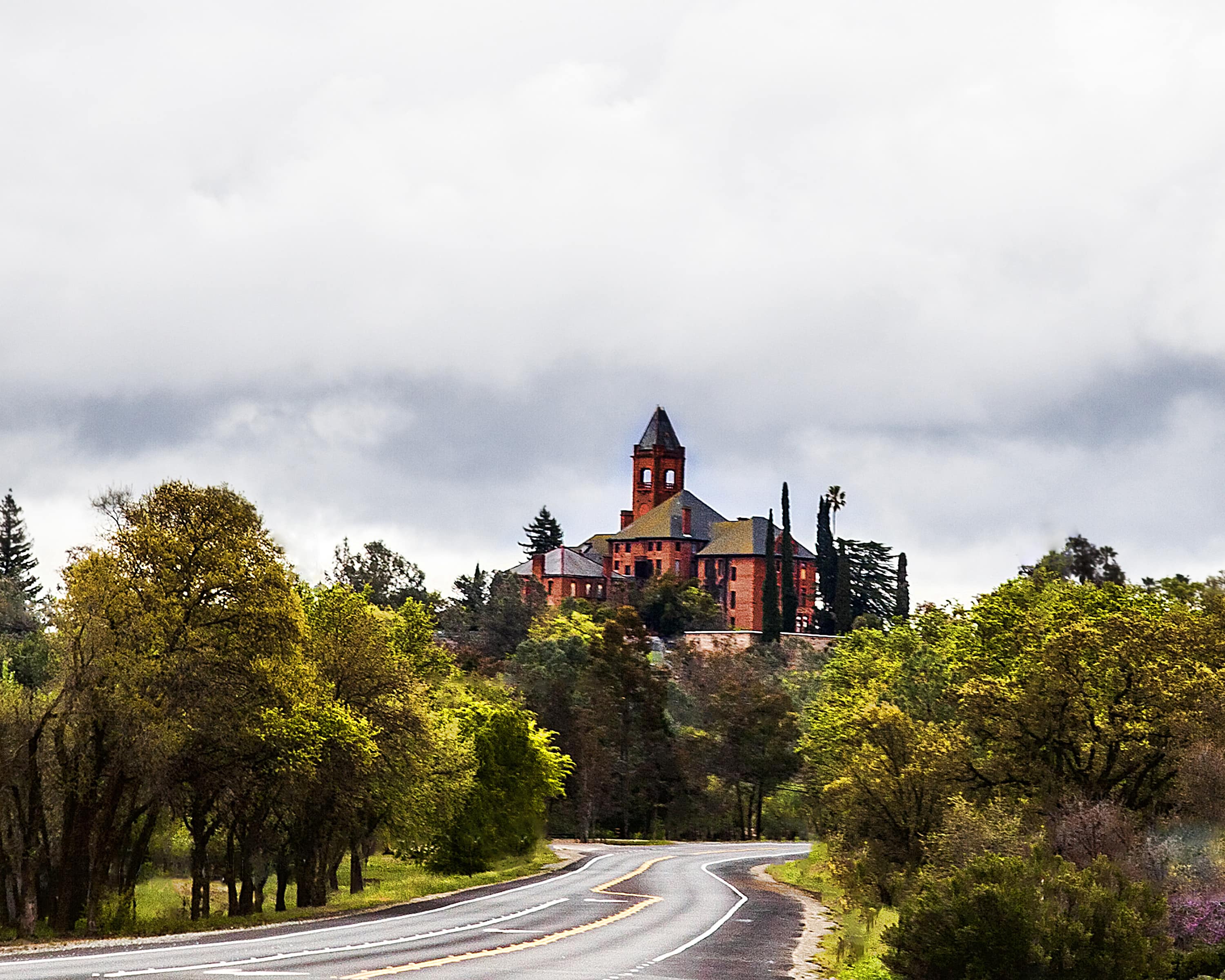 road leading up to Preston Castle with green trees and cloudy sky