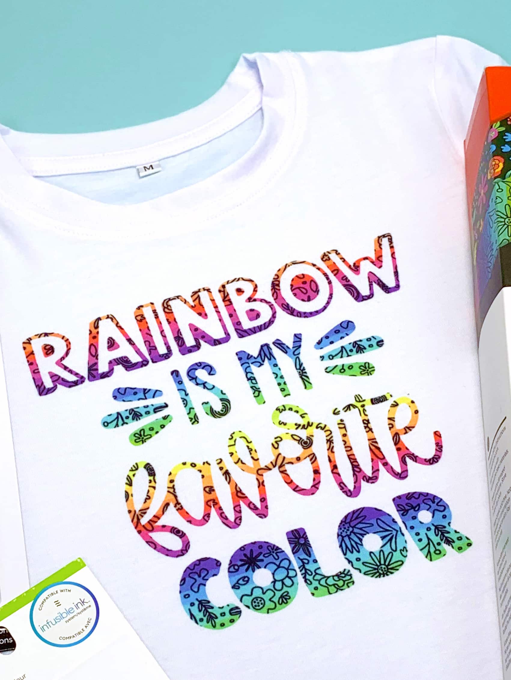 Close up view of white t-shirt with colorful "Rainbow is My Favorite Color" graphic design