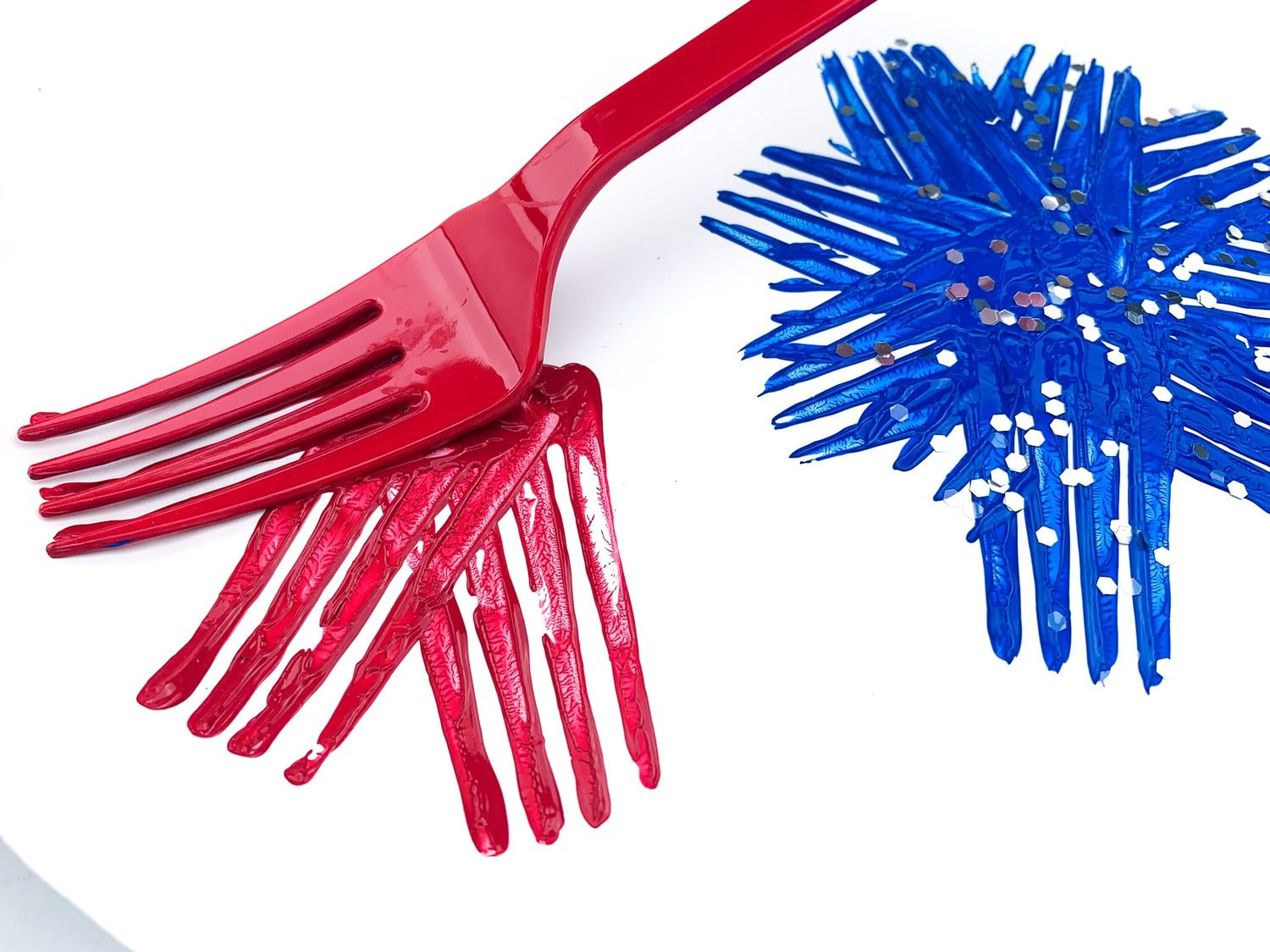 painted fork pressing firework pattern onto paper plate