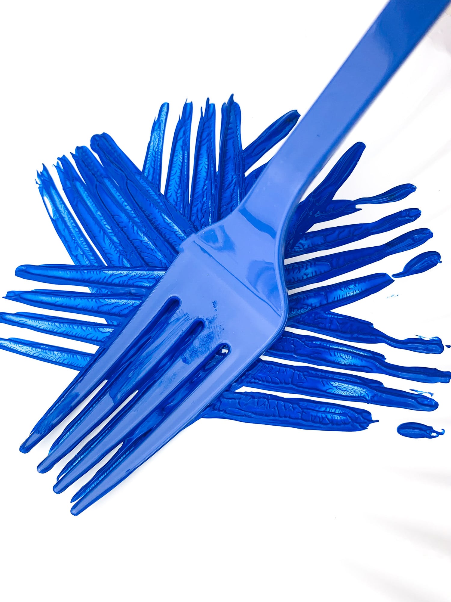 blue painted fork pressing firework pattern onto plate