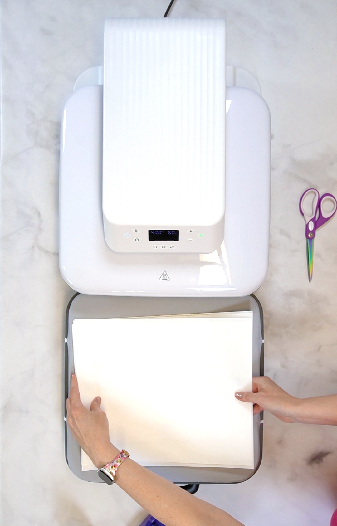 Hands placing a stack of papers on the mat of the HTVRONT Auto Heat Press