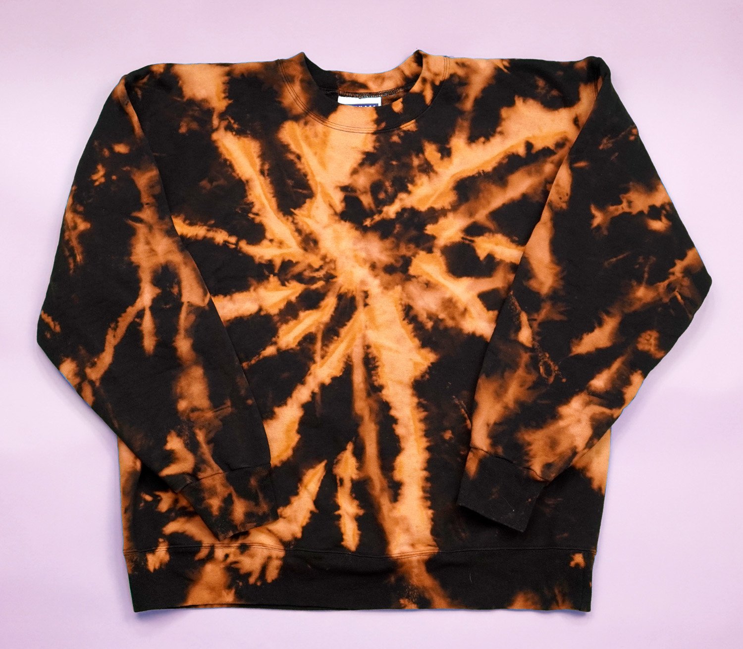 Black and rust orange bleach dyed sweatshirt on purple background