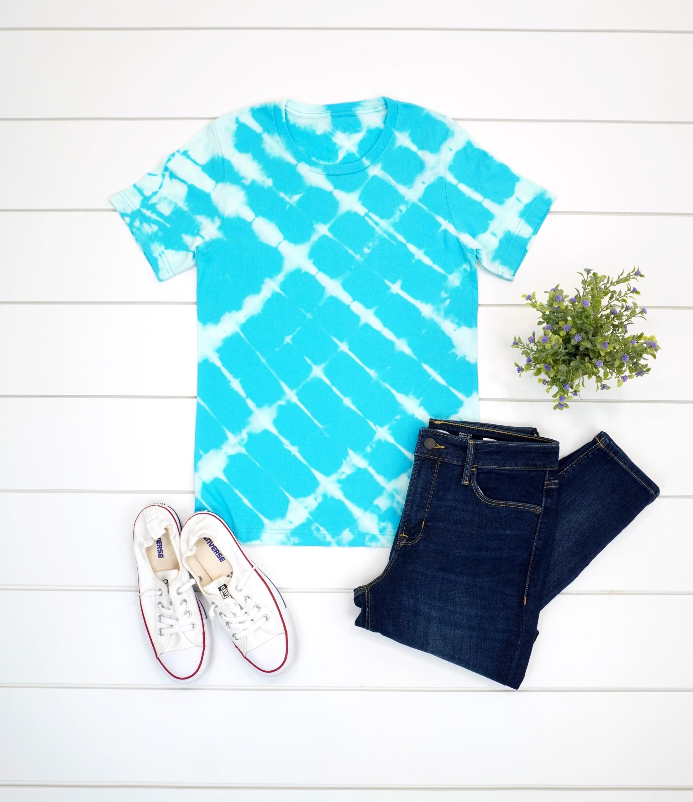 Aqua blue bleach tie dye t-shirt with outfit on white wood background