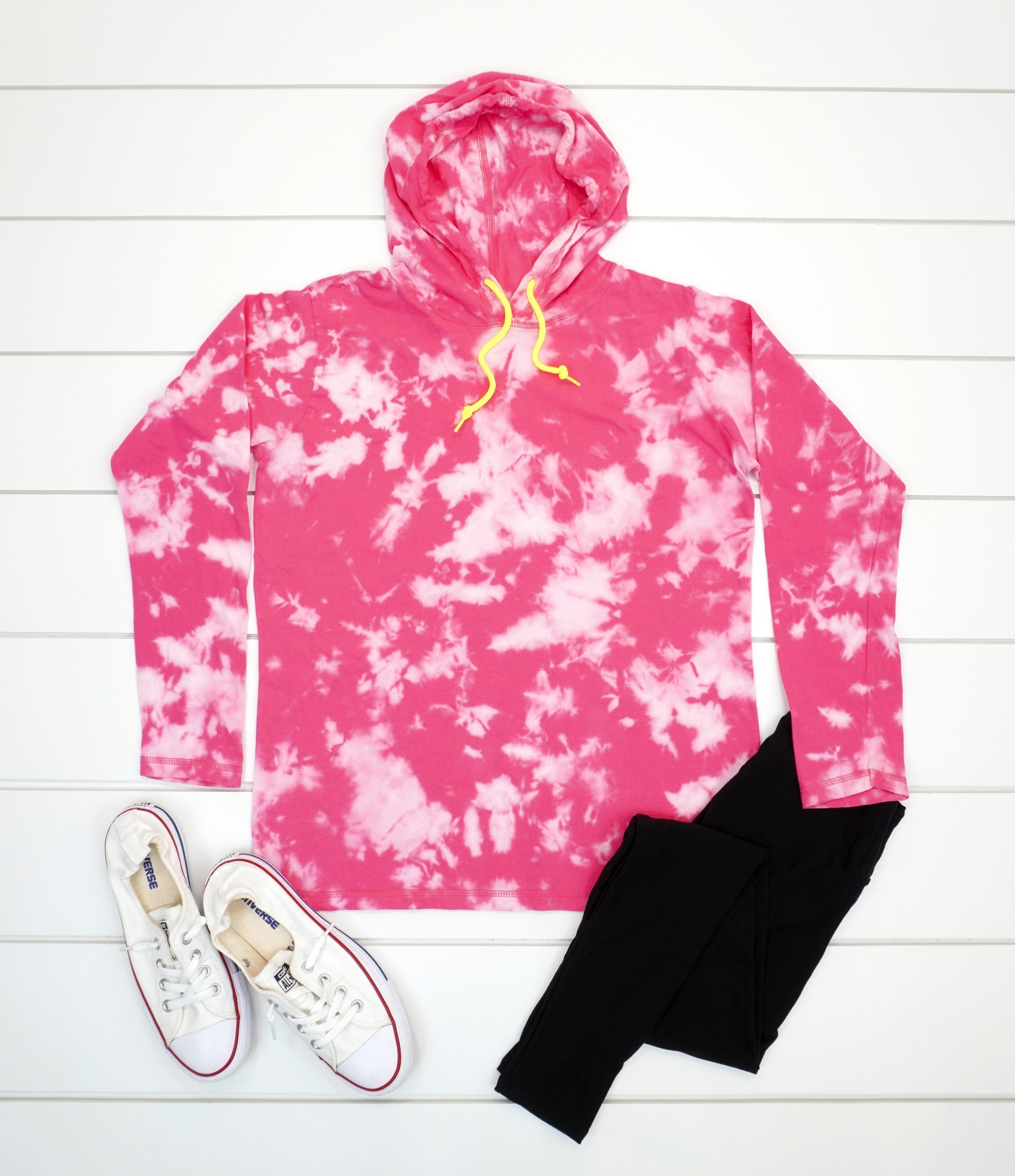Pink bleach tie dye hoodie with outfit on white wood background