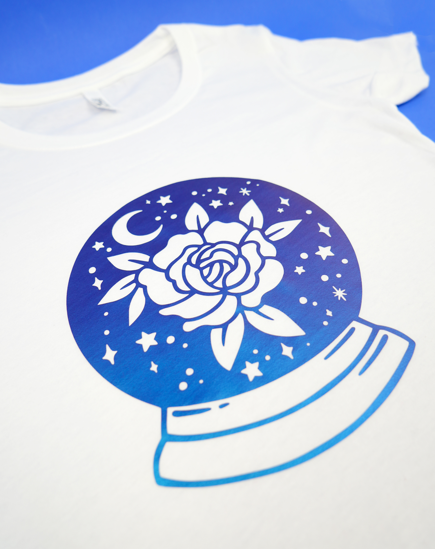 blue Color-Shift HTV design with rose and stars on white t-shirt on blue background