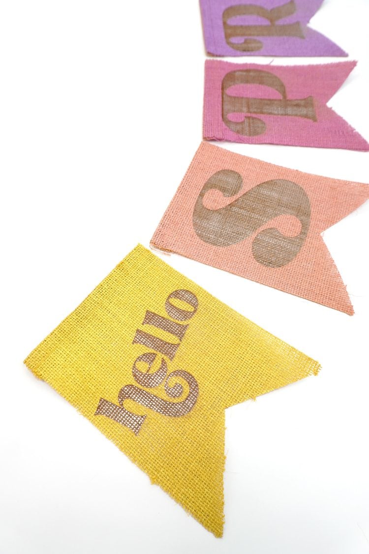 Close up of "Hello Spring" banner pieces made from colorful painted burlap on white background