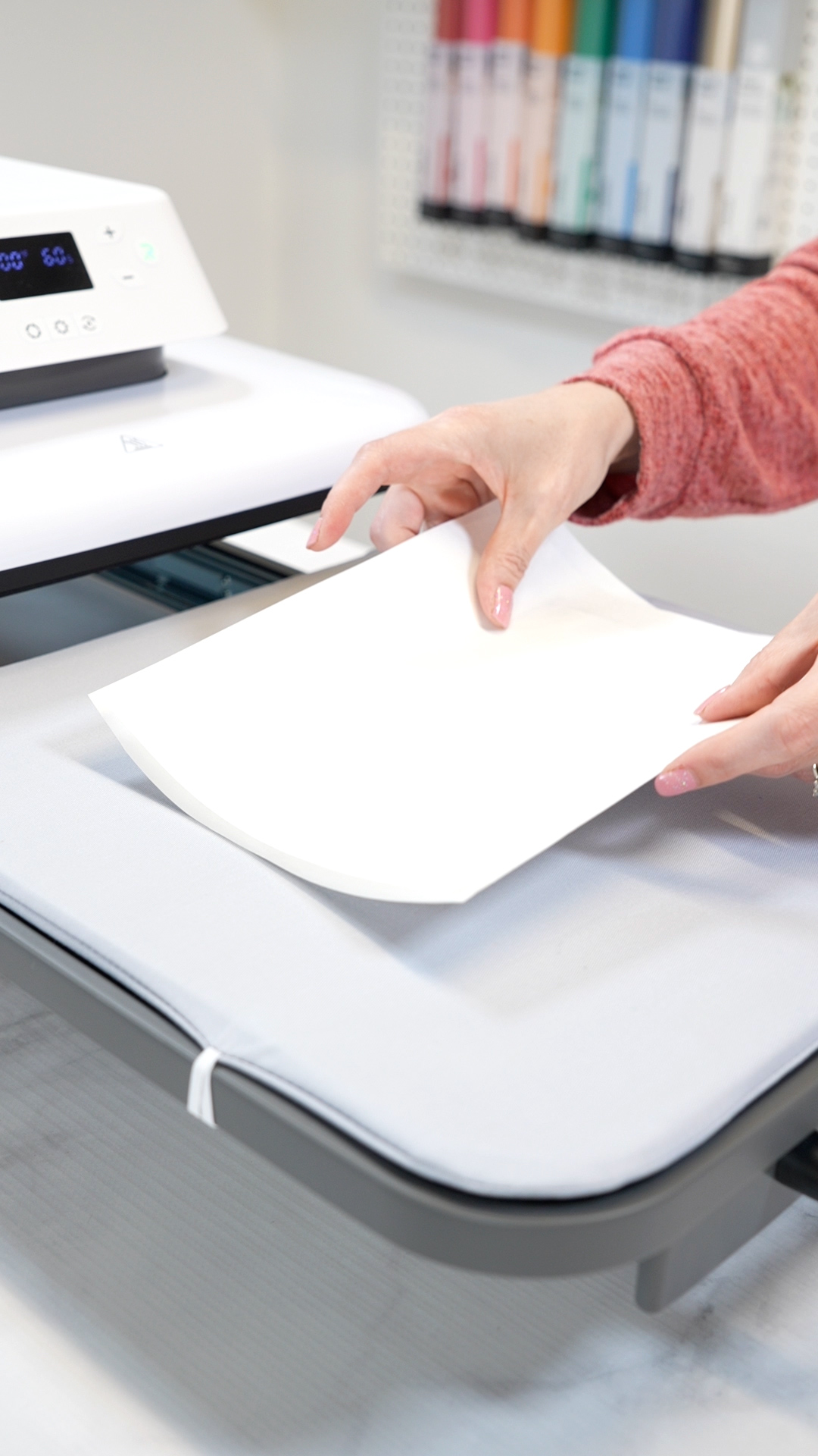 hands placing parchment paper over project on HTV heat press