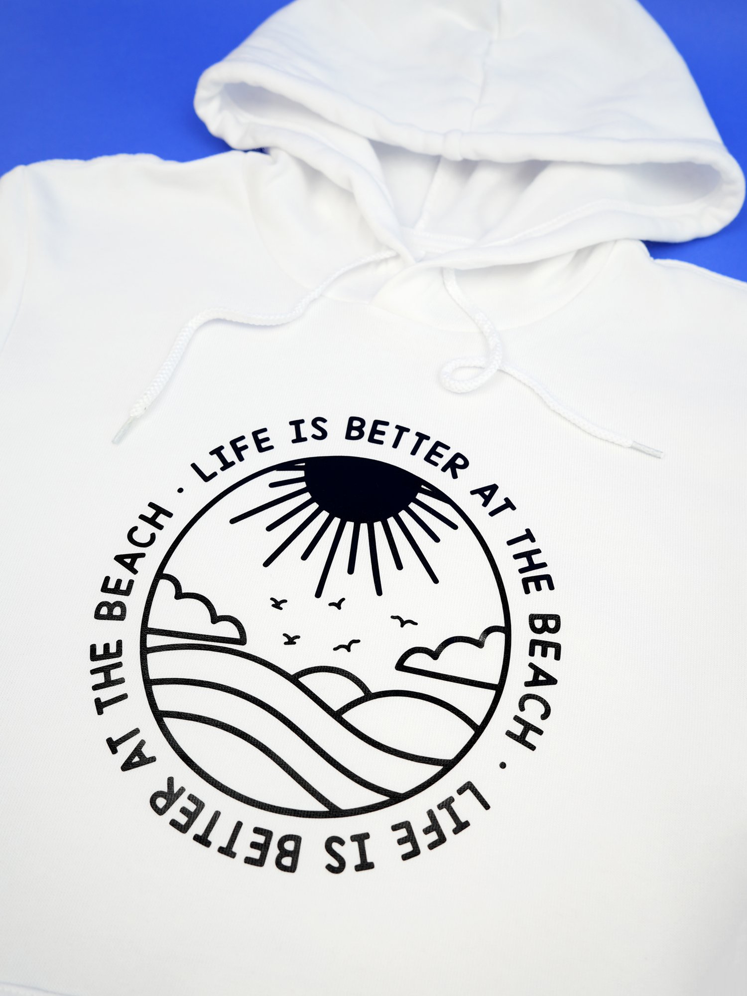 Close up of white hoodie with "Life is better at the beach" design in black