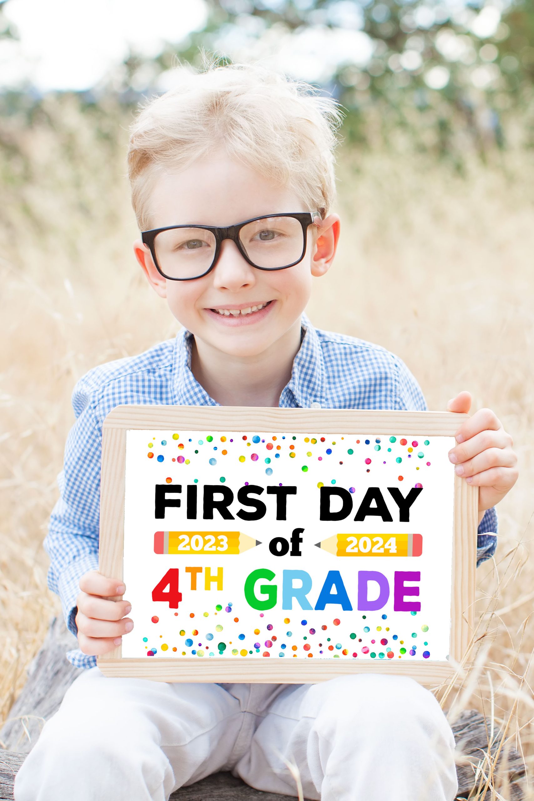Cute boy in glasses holding a free printable First Day of School sign