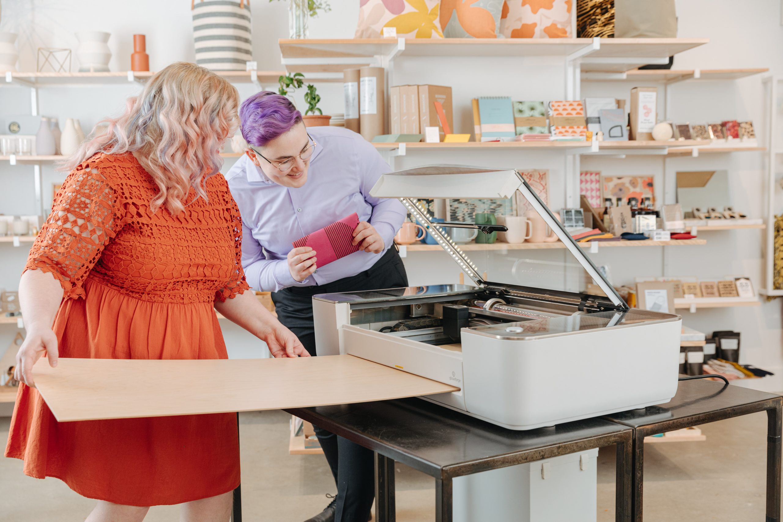 Woman in orange dress using the Glowforge Pro Passthough with a large sheet of wood