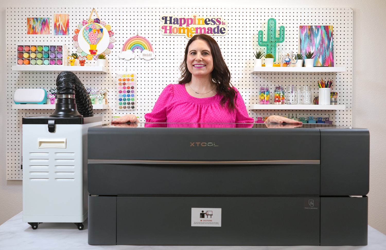 Dark haired woman standing behind the xTool P2 machine and riser base