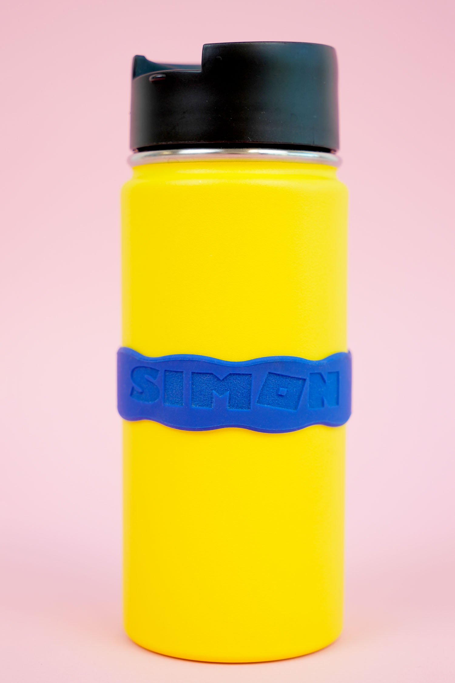yellow metal water bottle with blue silicone band engraved with the name Simon