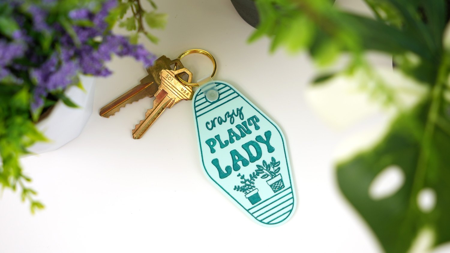 "Crazy plant lady" motel-style acrylic keychain surrounded by plants
