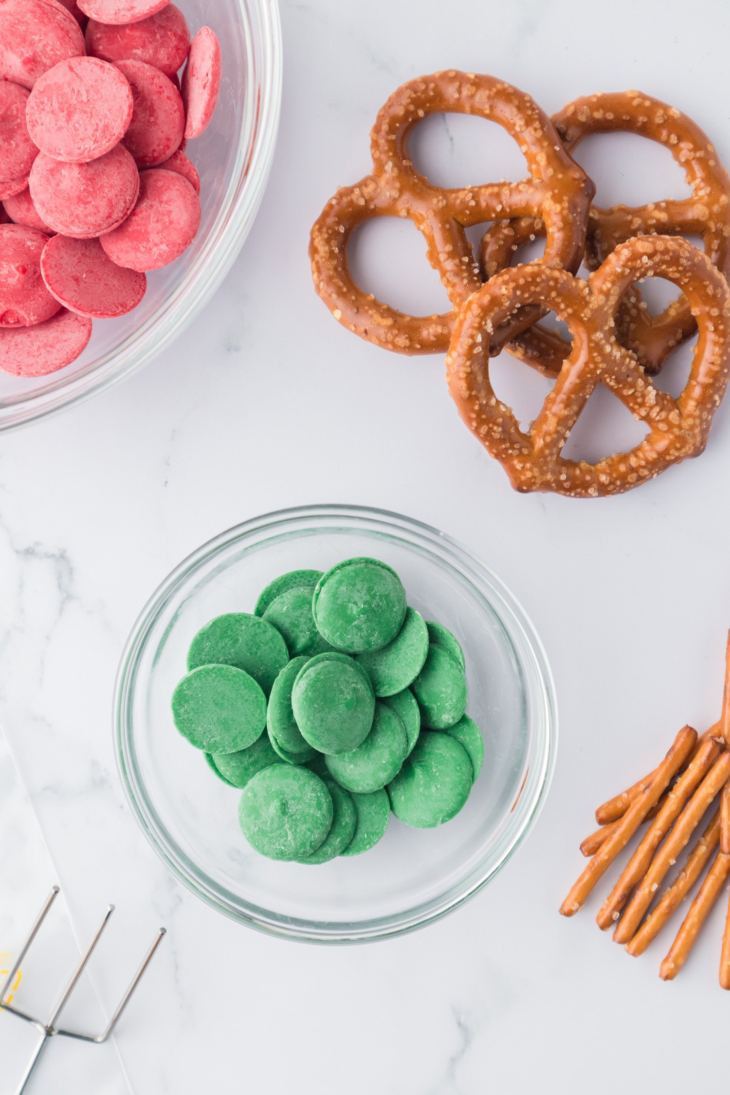 green candy melts in bowl with pretzels nearby