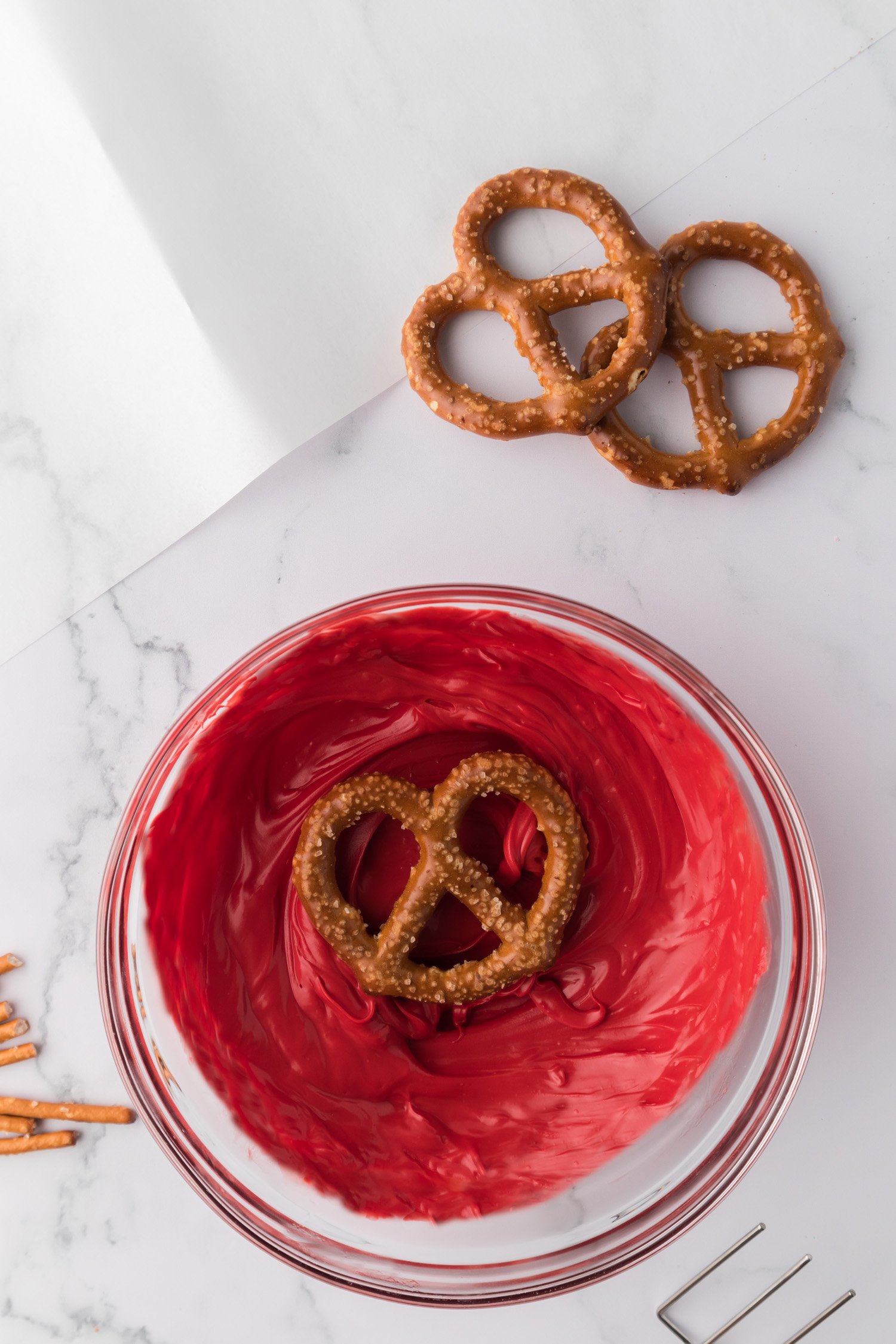 pretzel in bowl of melted red chocolate