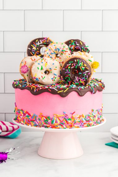 sprinkled pink cake topped with donuts