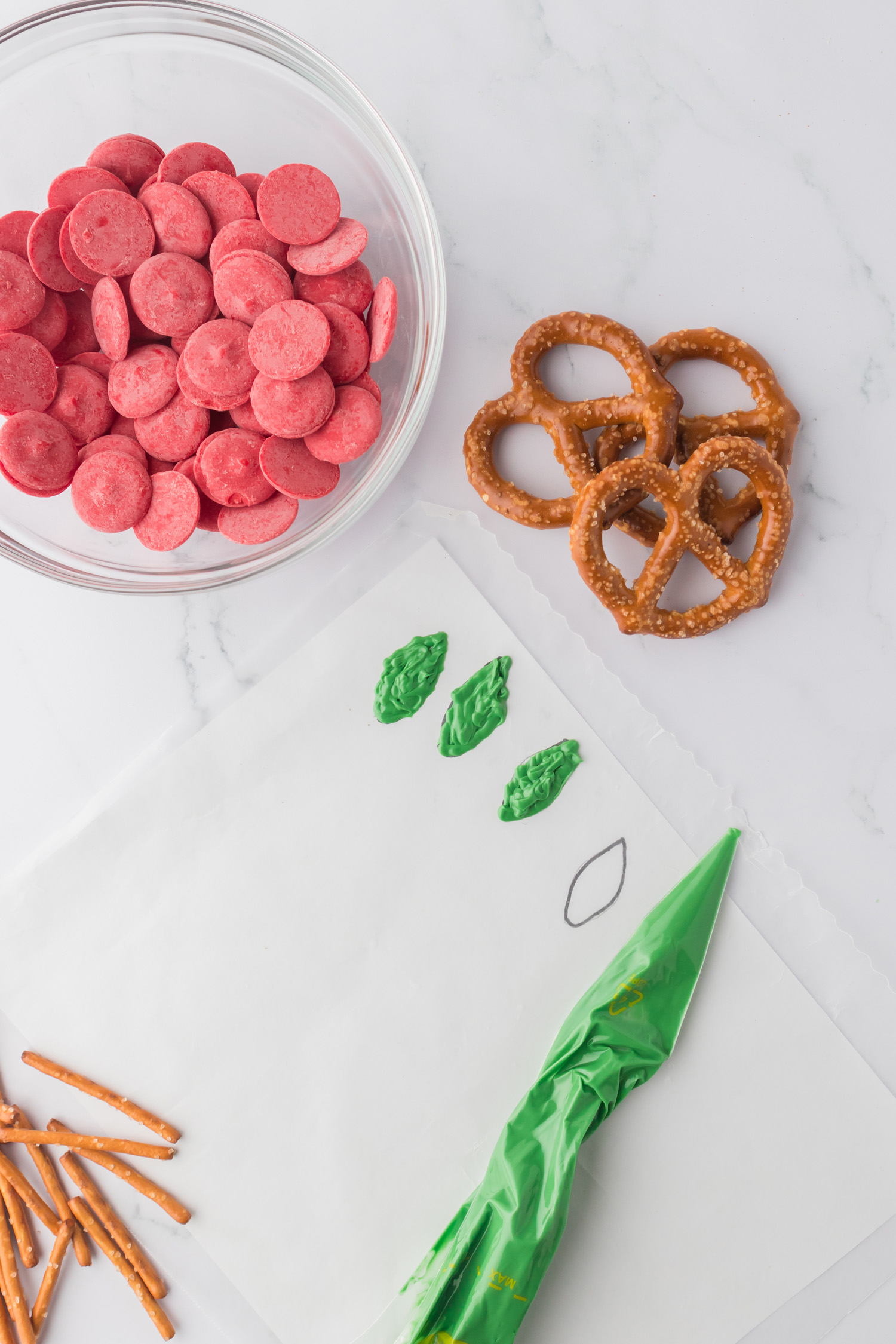 green melted chocolate piped into the shape of leaves on wax paper with supplies