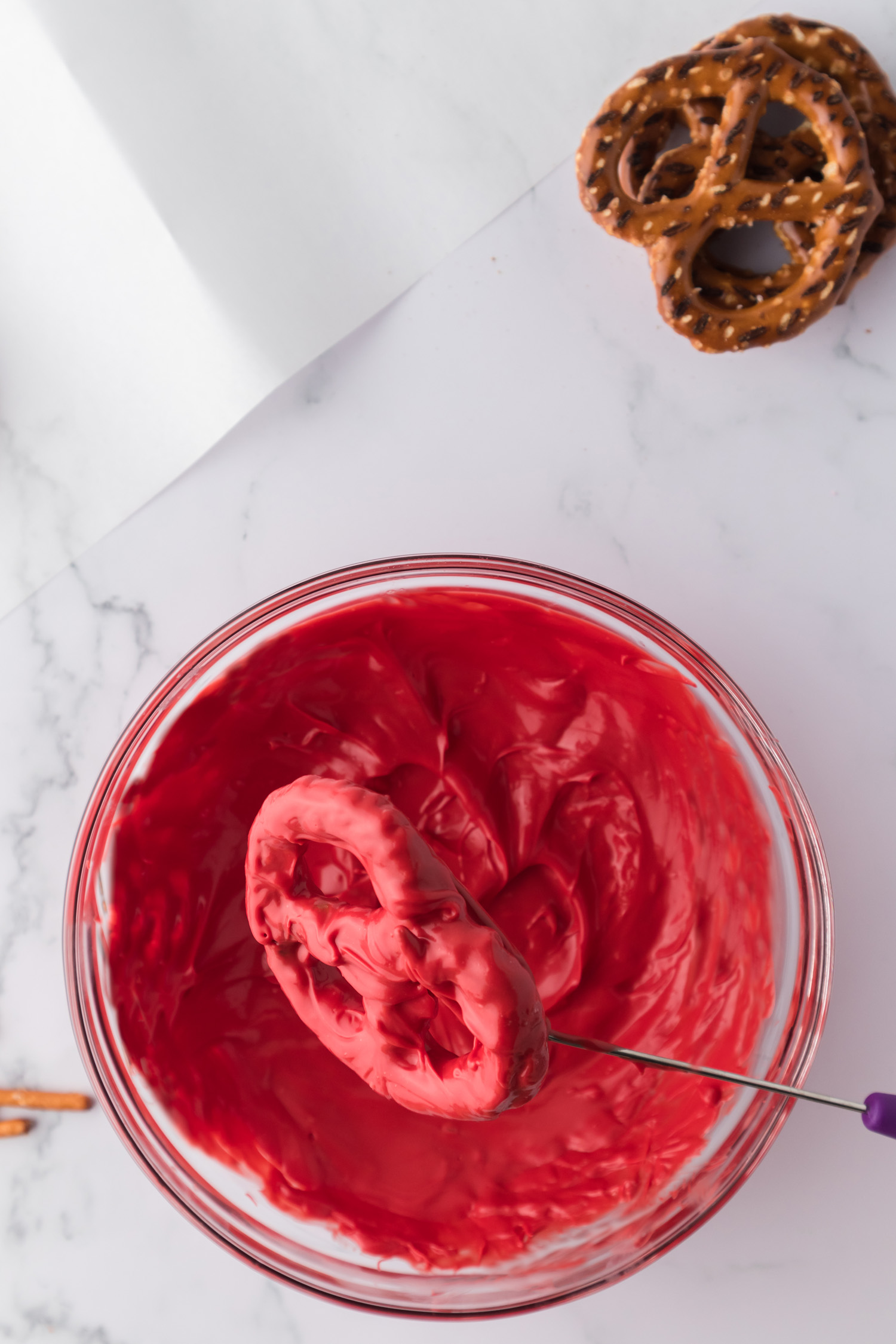 dipping pretzel into red melted chocolate