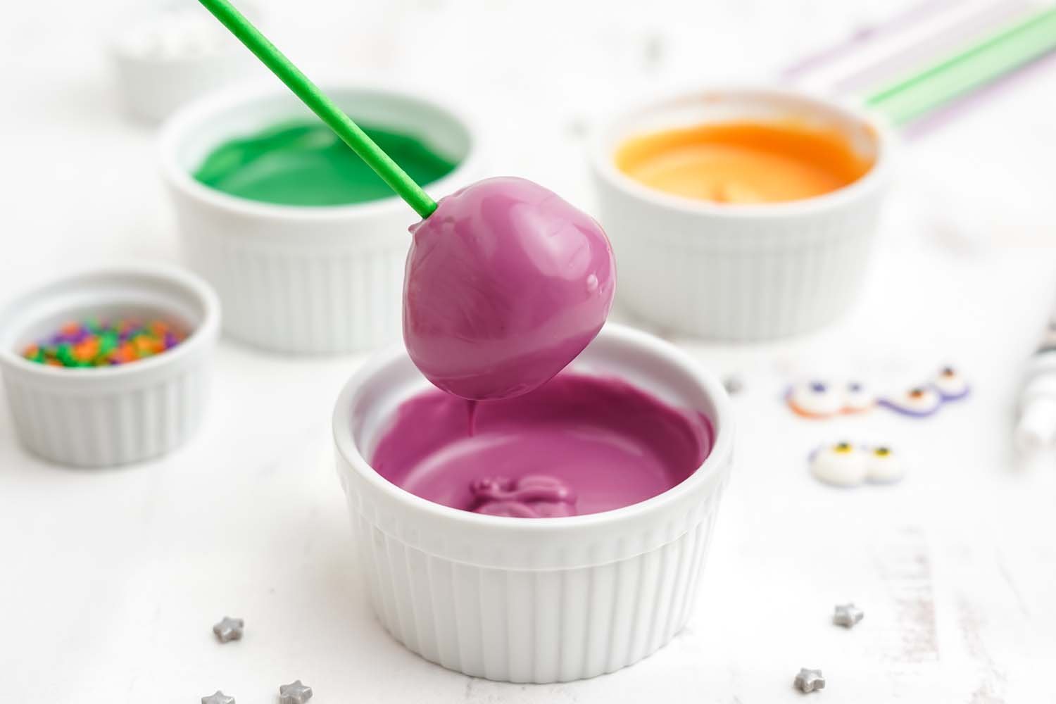 dipping donut hole into purple candy melts with other candies
