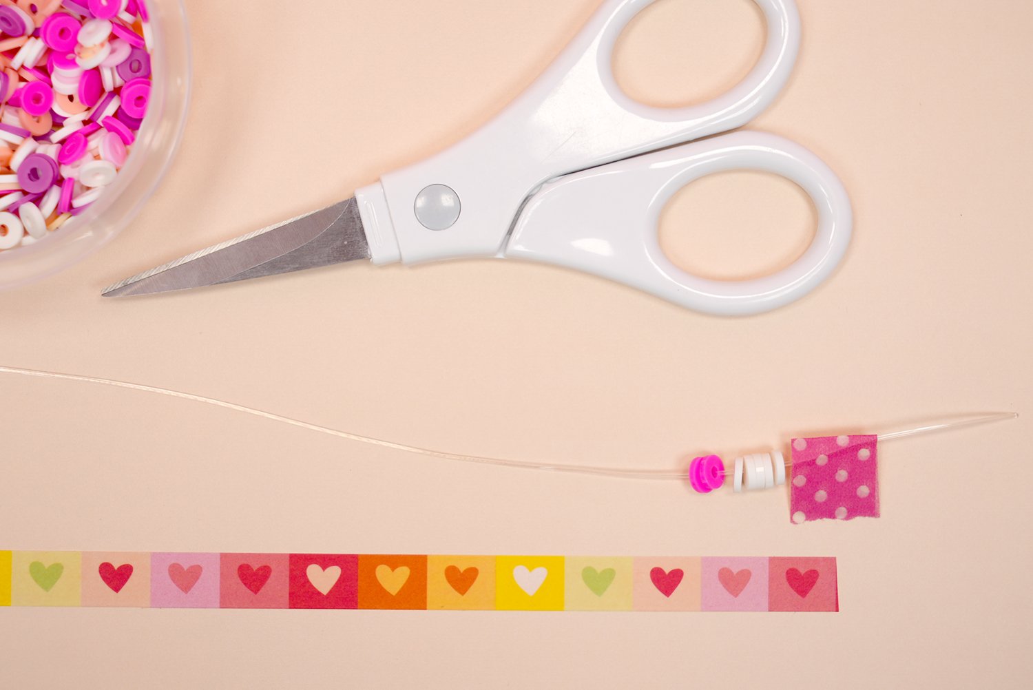 Close up of beads on a string with scissors and measuring washi tape