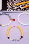 Close up of "Teach" teacher bracelet that looks like pencils on purple background