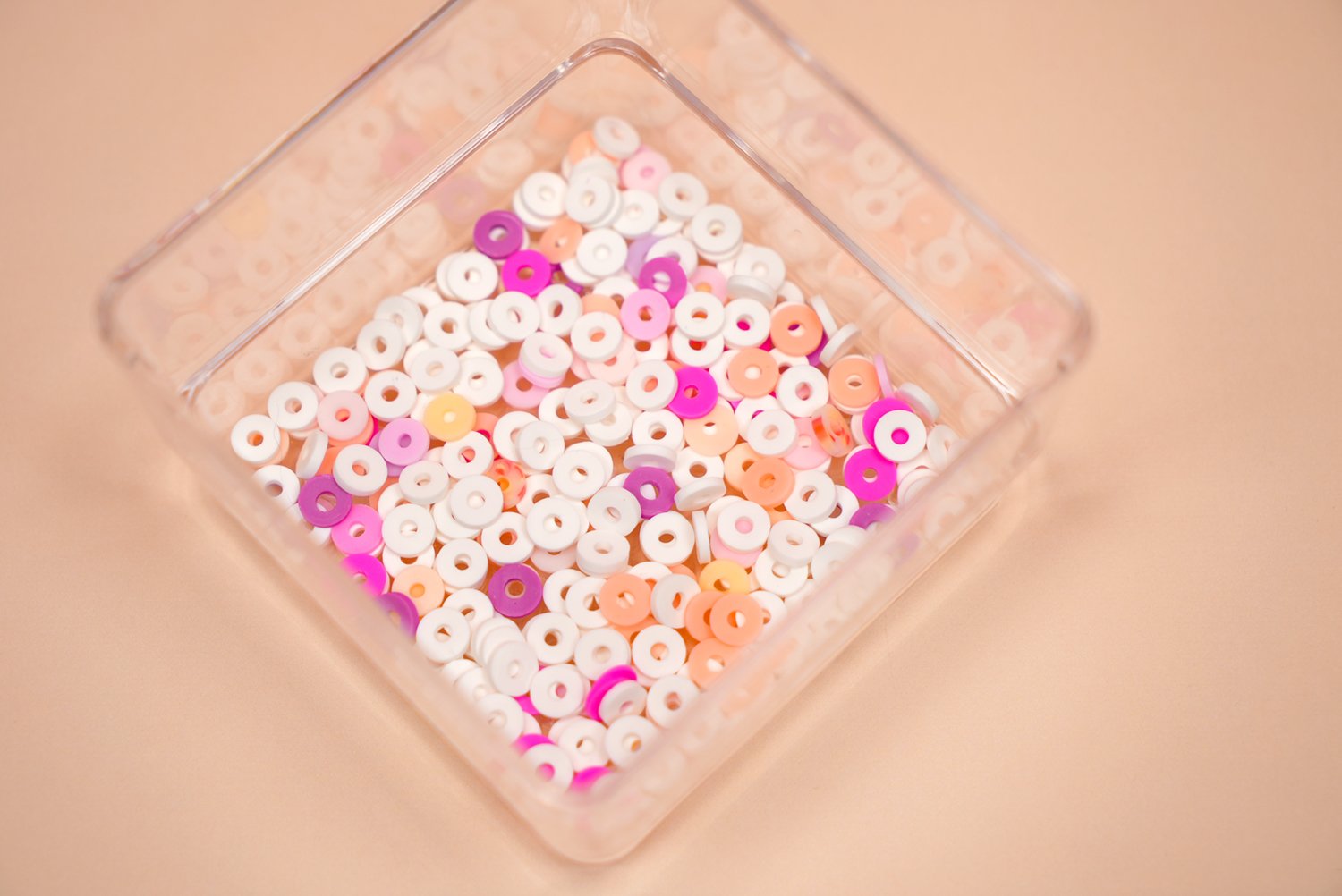 Close up image of small, square dish with a mixture of white and sunset-hued clay beads