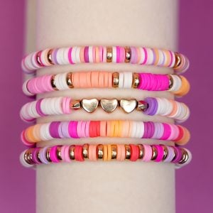 Close up of heishi clay bead bracelets - colorful preppy clay bead bracelet set on display stand on purple background