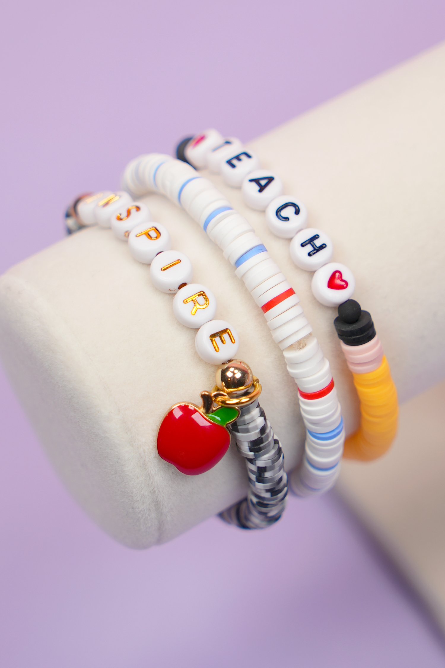 Close up view of three teacher bracelets made of clay beads on a display stand